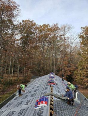 A group of people are working on a roof in the woods