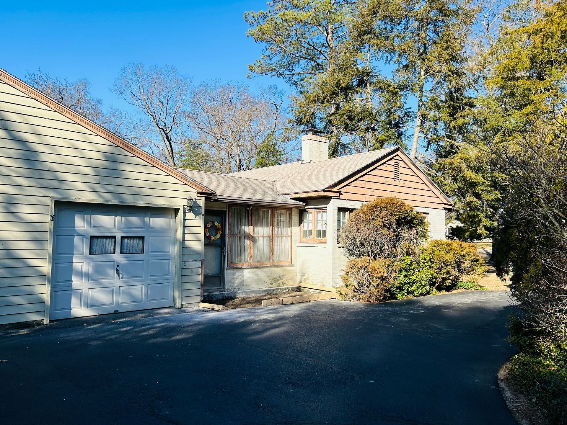A small house with a garage and a driveway in front of it.