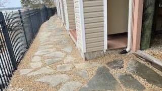 a stone walkway leading to a house next to a fence .