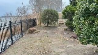 a fence surrounds a dirt path leading to a body of water .