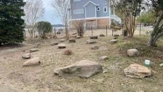 there are a lot of rocks in the grass in front of a house .
