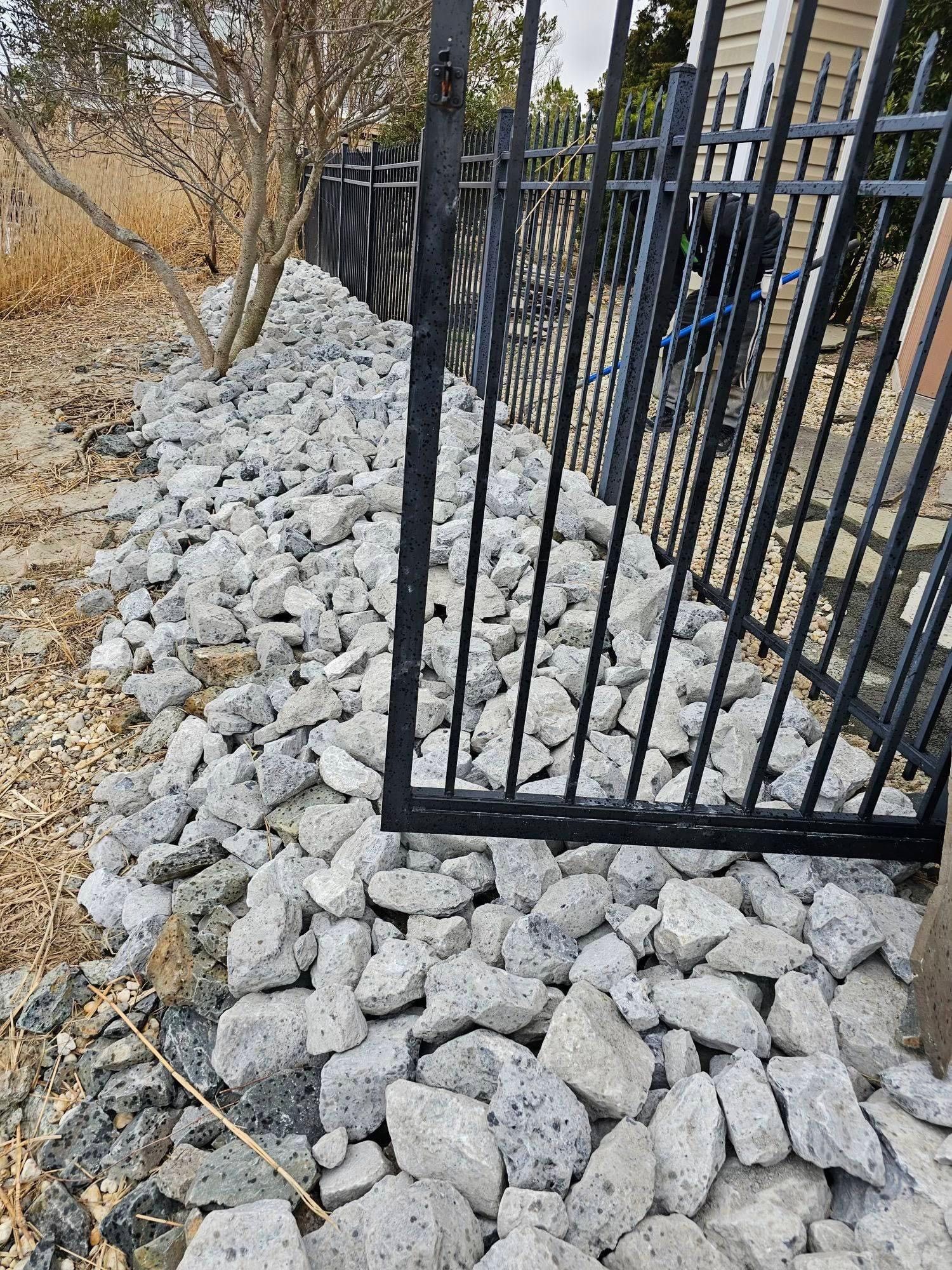 a pile of rocks next to a fence and a gate .