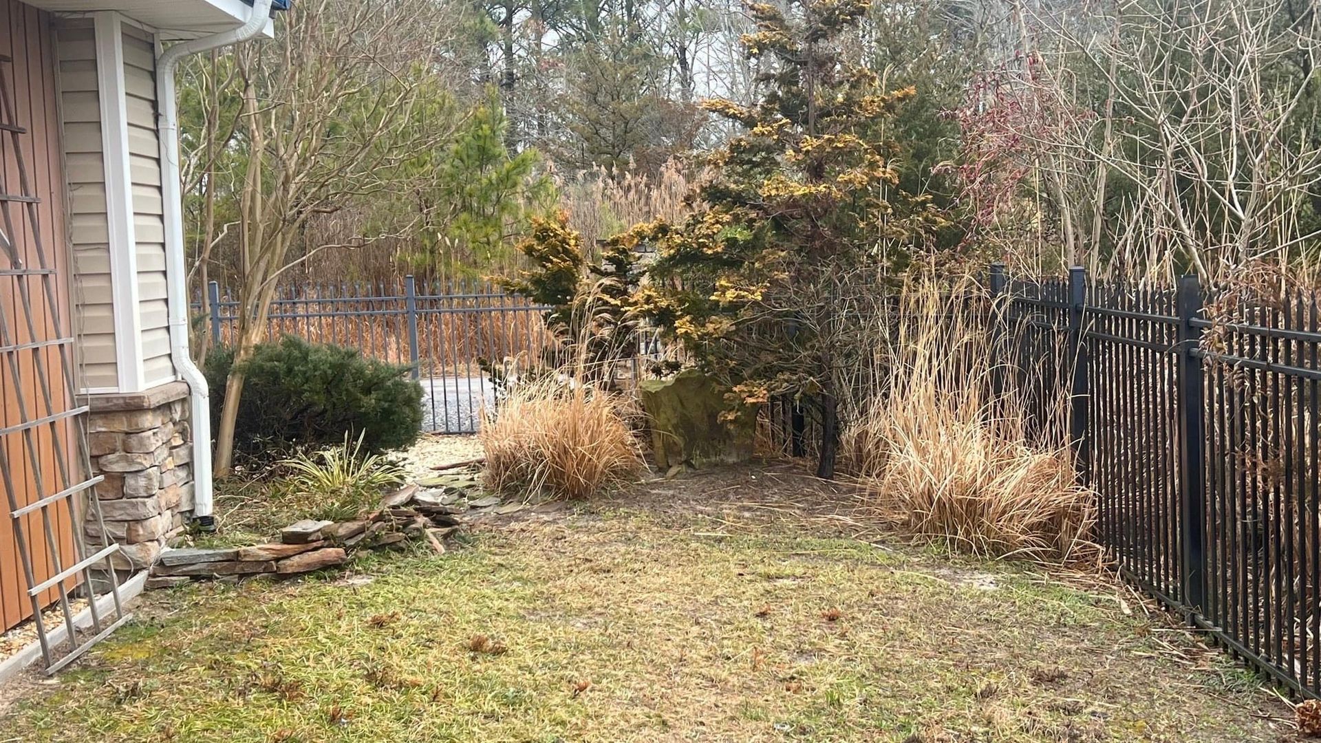 a backyard with a fence and a house in the background .