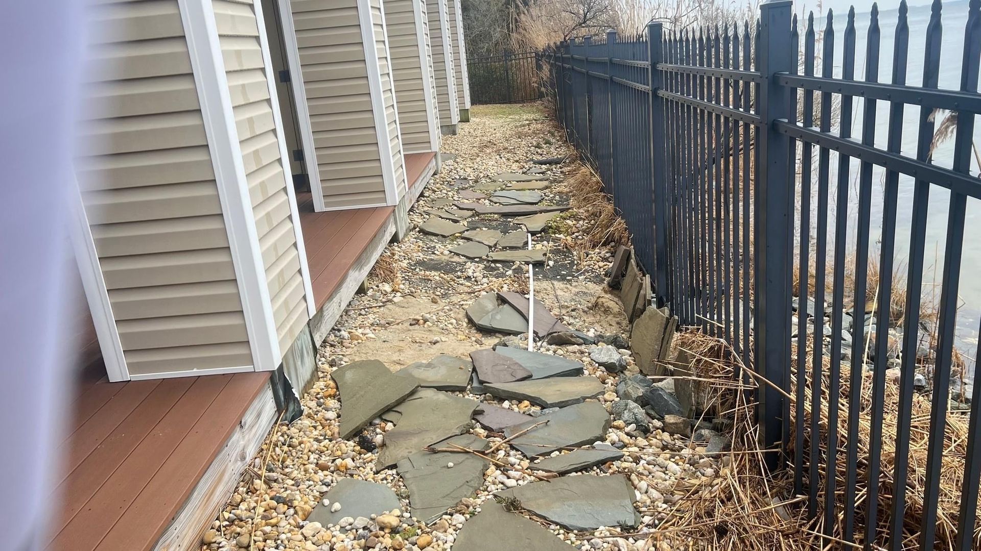 a stone walkway next to a fence and a building