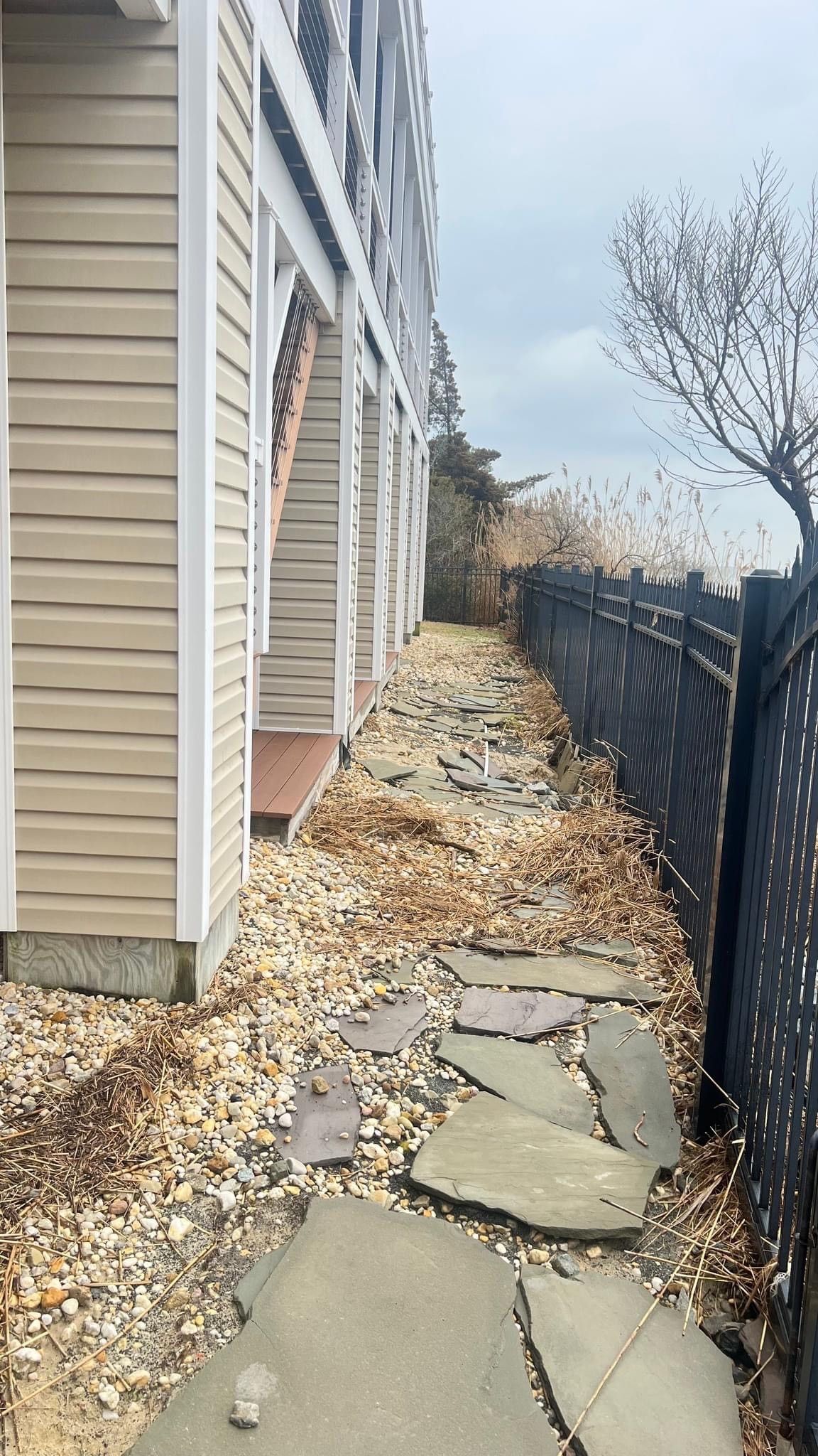 a stone walkway leading to a building next to a fence .