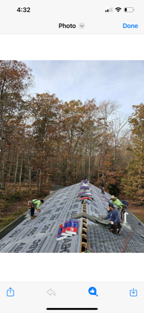 A group of people are working on a roof in the woods.
