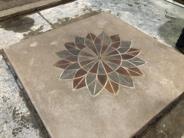 Concrete slab with a decorative flower mosaic in brown, gray, and red tiles