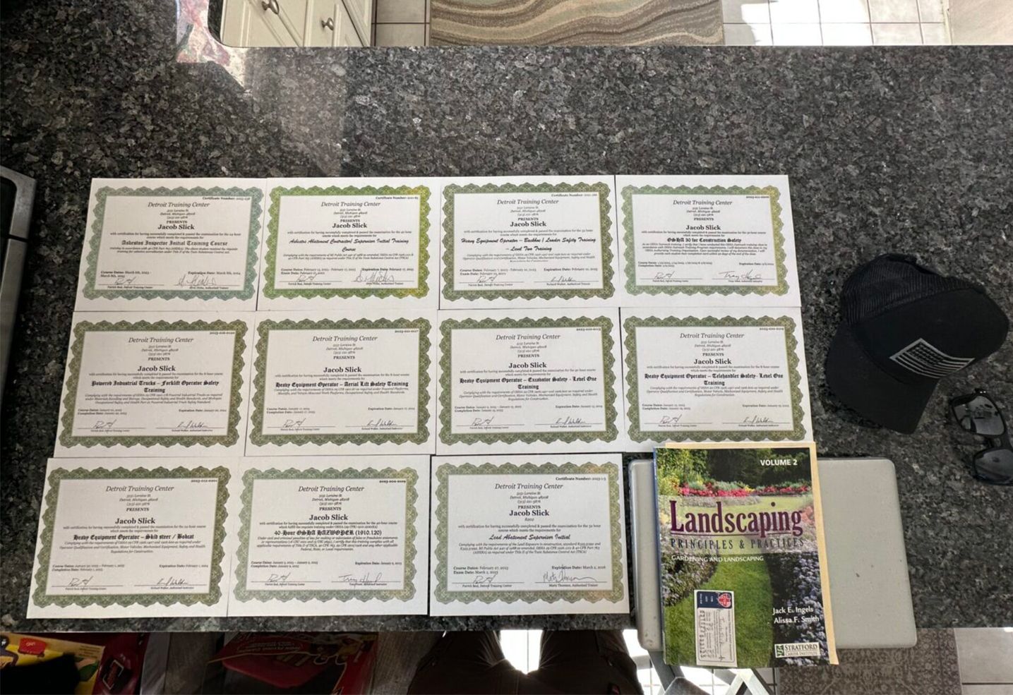 Display of framed certificates arranged on a dark table beside a magazine and booklet.