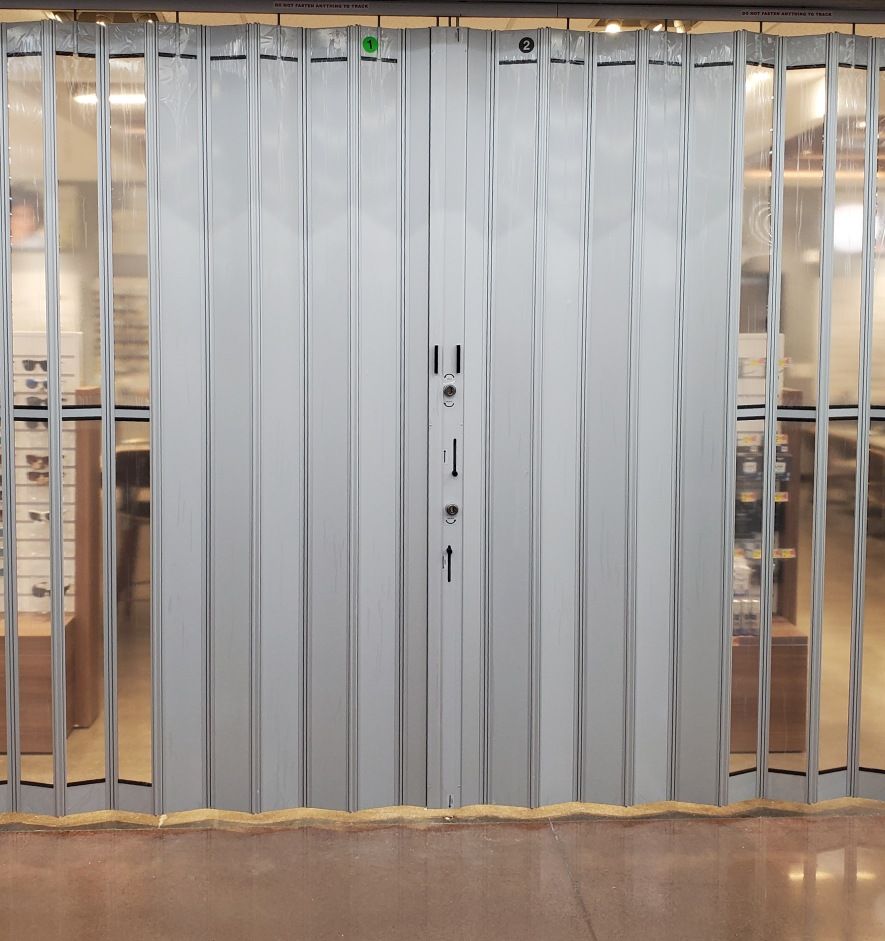 A sliding glass door with a clear curtain behind it.