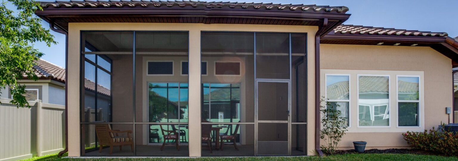 A screened in porch in the backyard of a house.