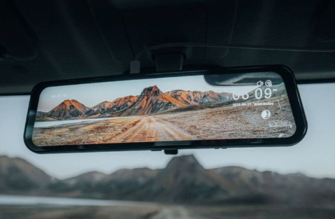 A dash cam is hanging from the windshield of a car.