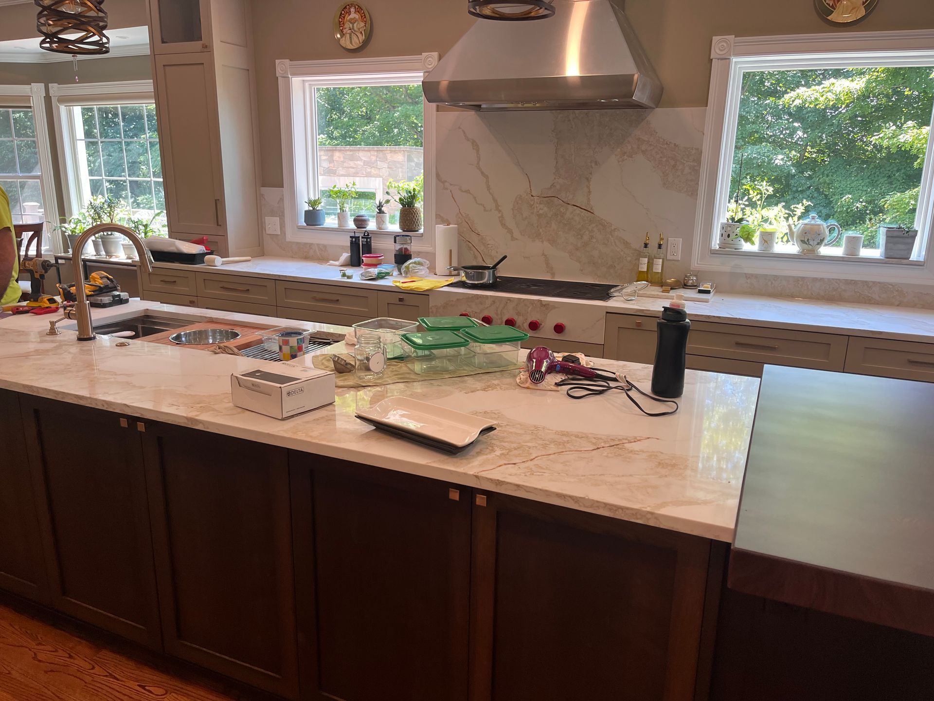 A kitchen with a sink, stove, and two windows.