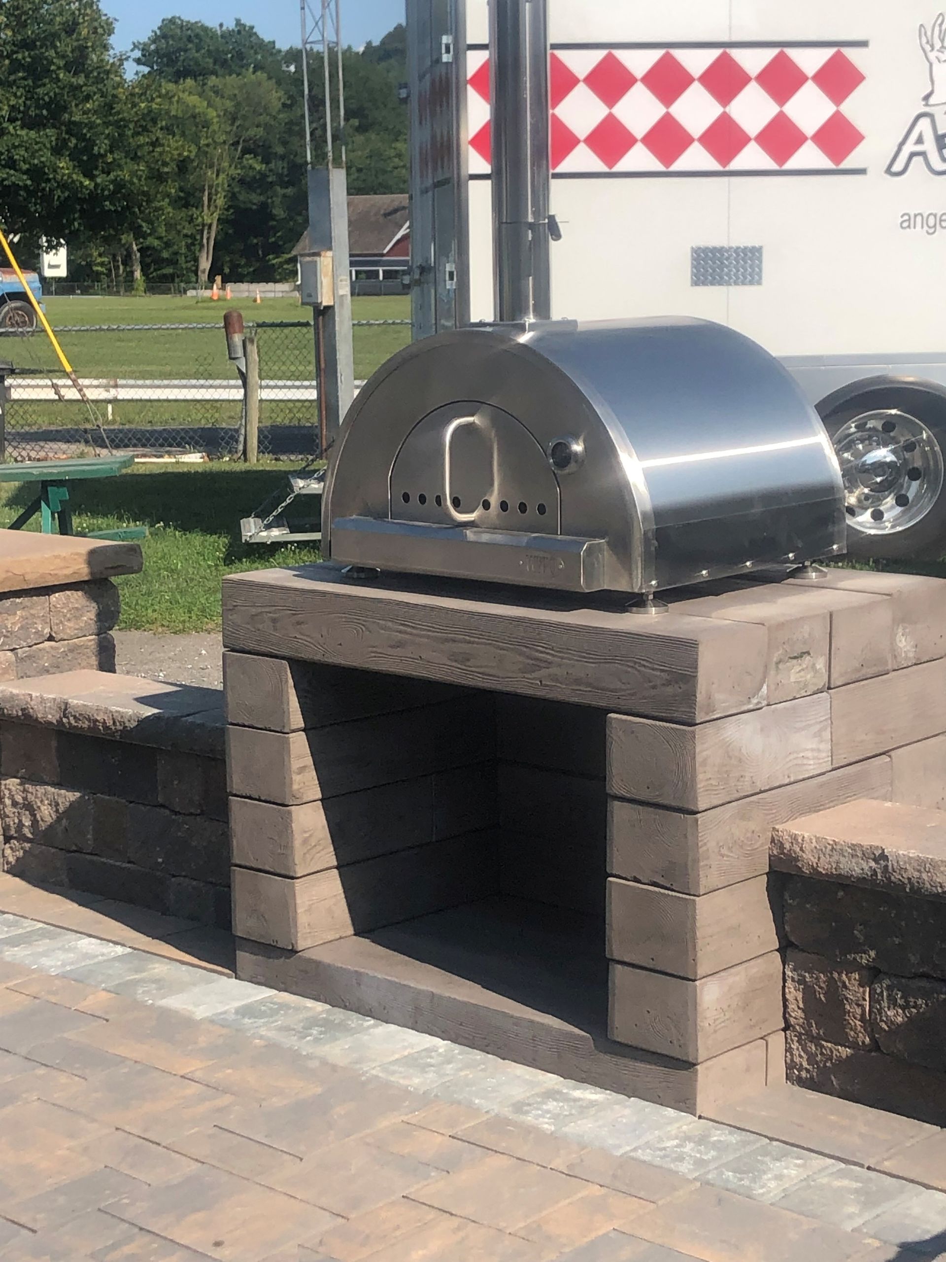 A stainless steel pizza oven is built into a brick wall