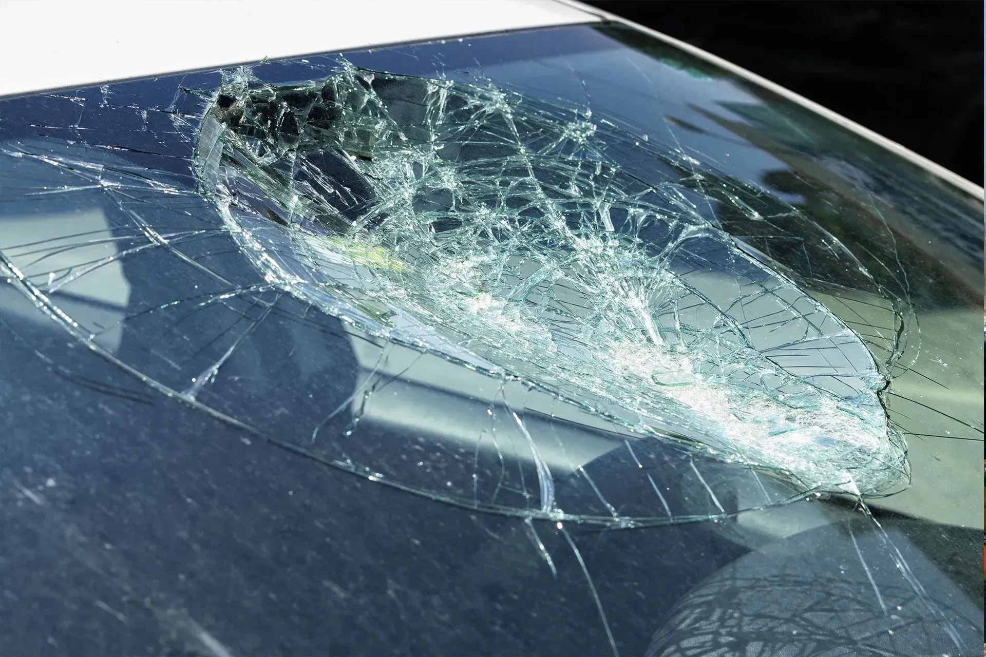 Broken car windshield; extensive cracking and hole in the center.