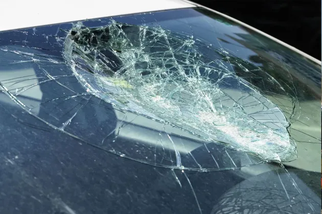 Broken car windshield; extensive cracking and hole in the center.