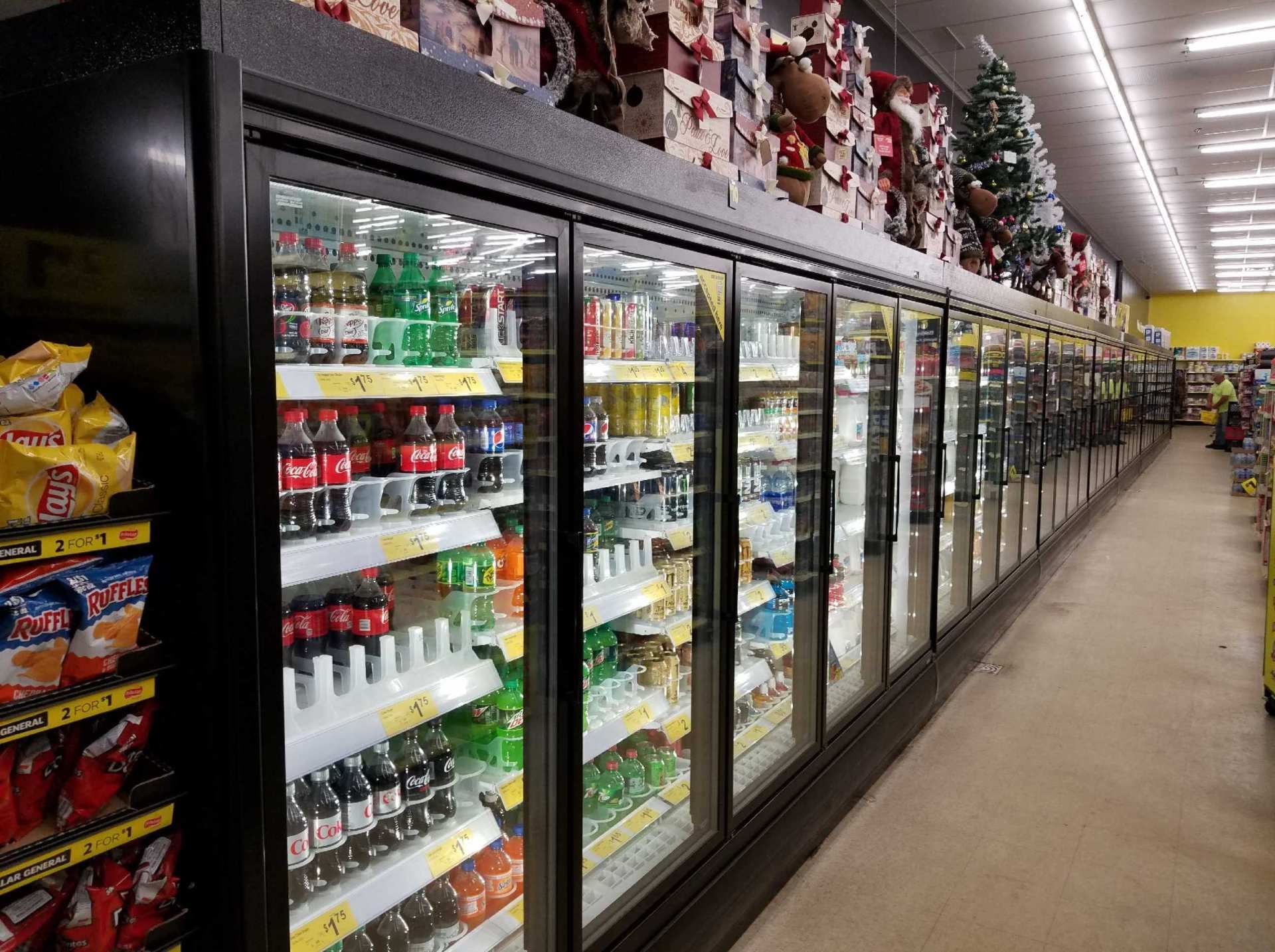 Grocery store aisle with glass-door refrigerated drink and dairy cases along one side.