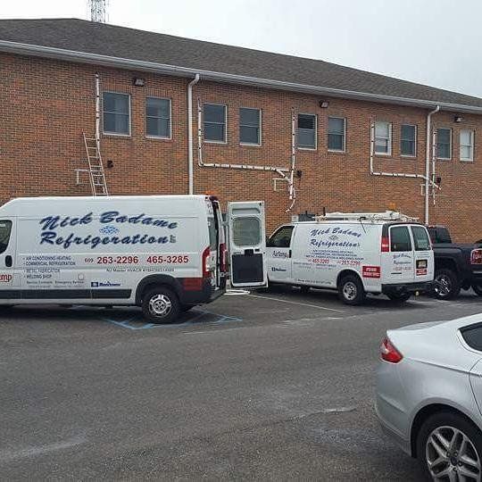 White moving vans parked outside a brick building on a cloudy day
