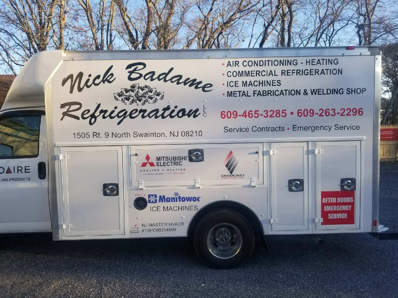 White Nick Badame Refrigeration service trailer with business contact details parked outdoors