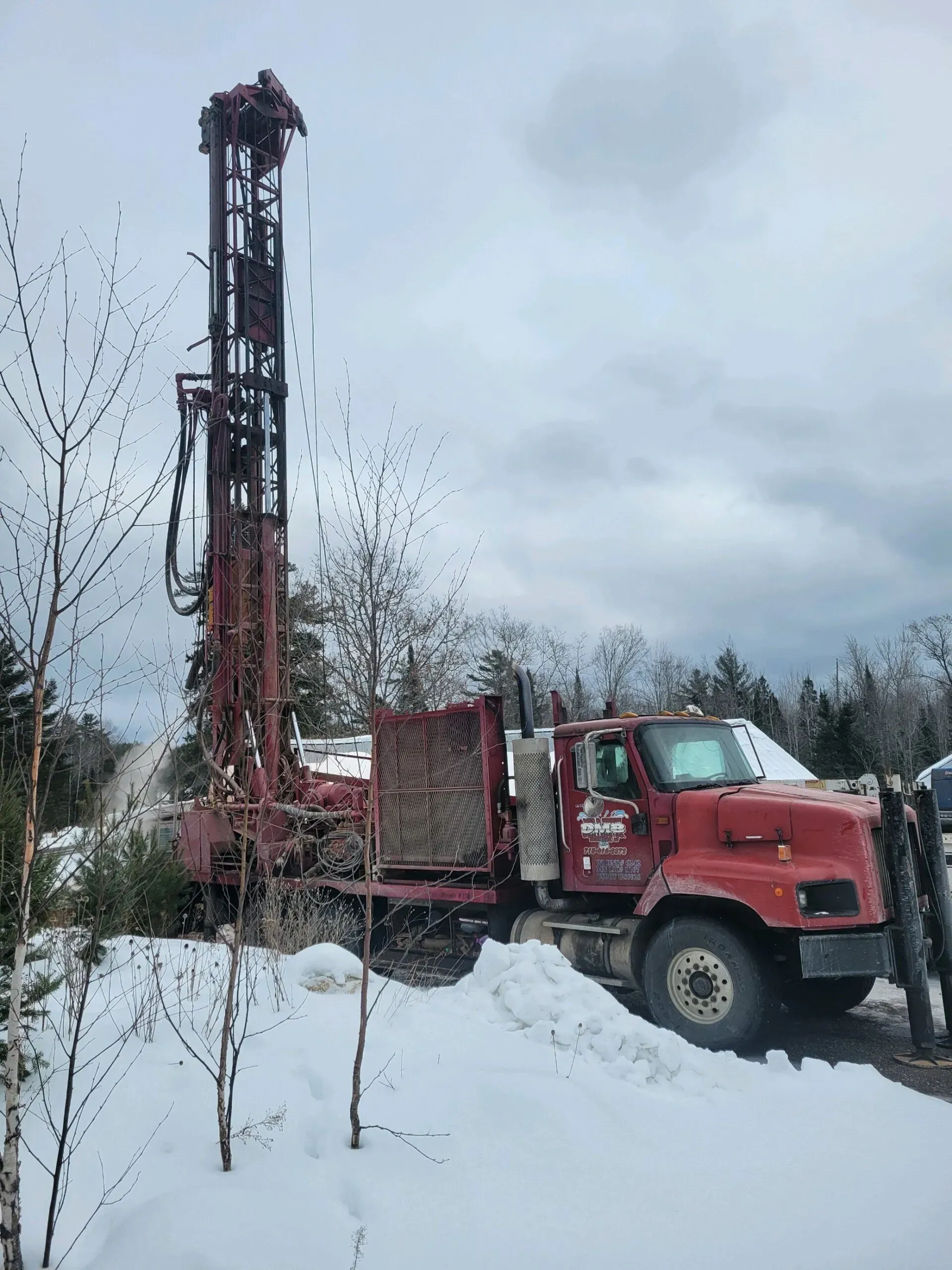 Red drilling rig in a snowy landscape.