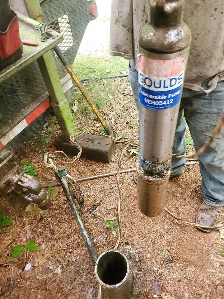 Person holding a Goulds Submersible Pump showing mud. Outdoor setting.