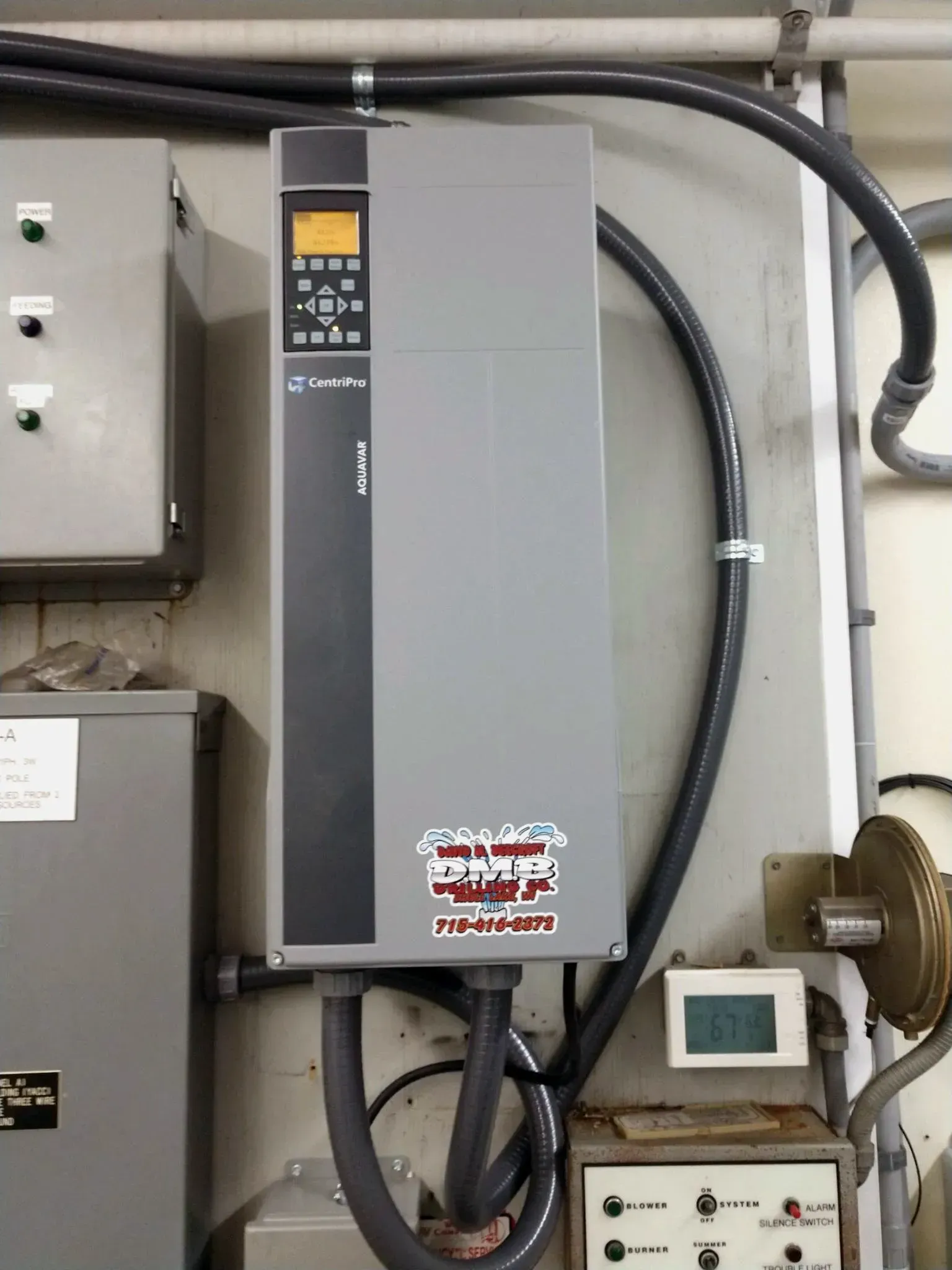 Gray industrial electrical panel mounted on a wall, with conduit and control panel.