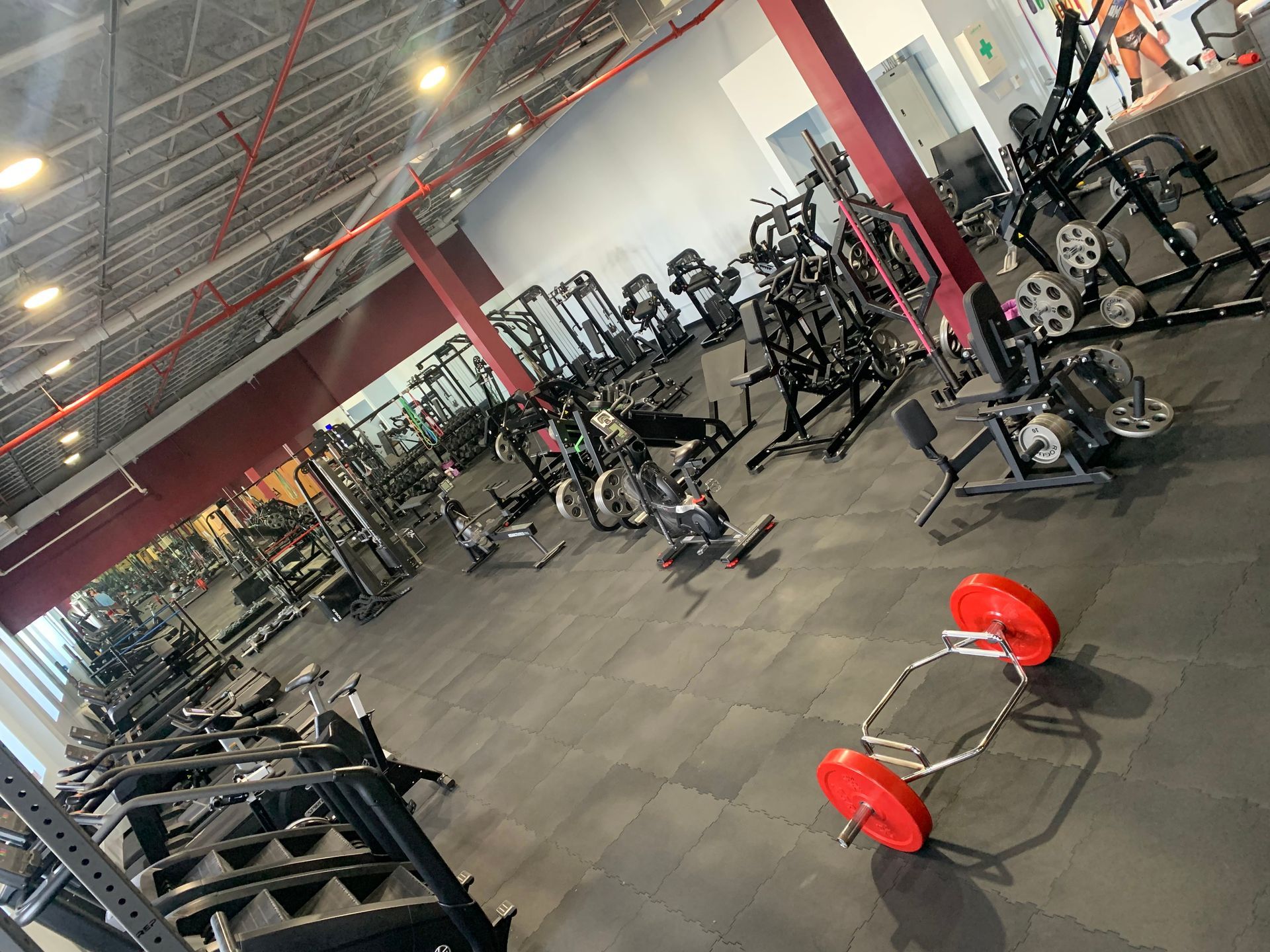 A gym filled with lots of exercise equipment and a barbell on the floor.