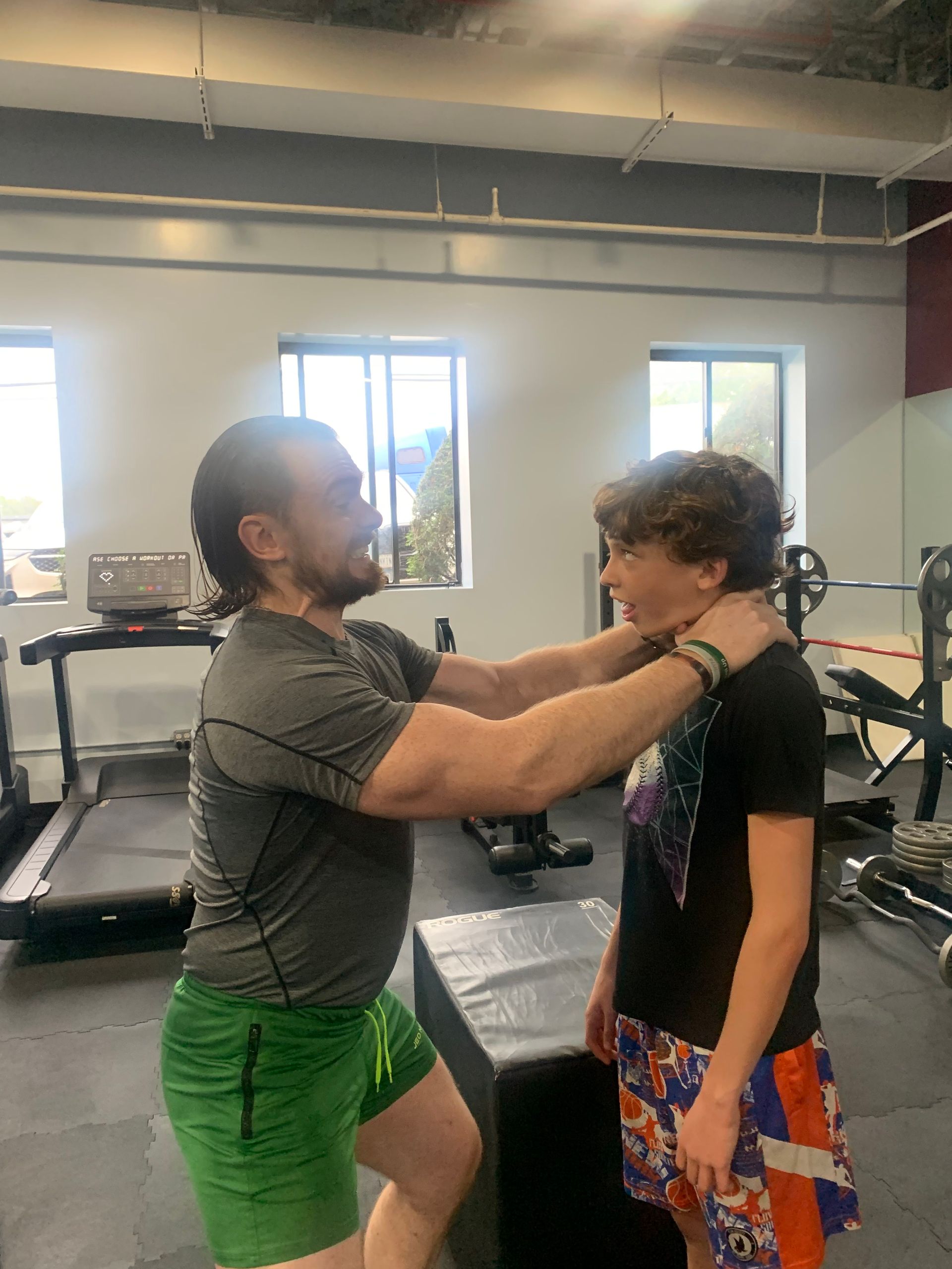 A man and a boy are standing next to each other in a gym.