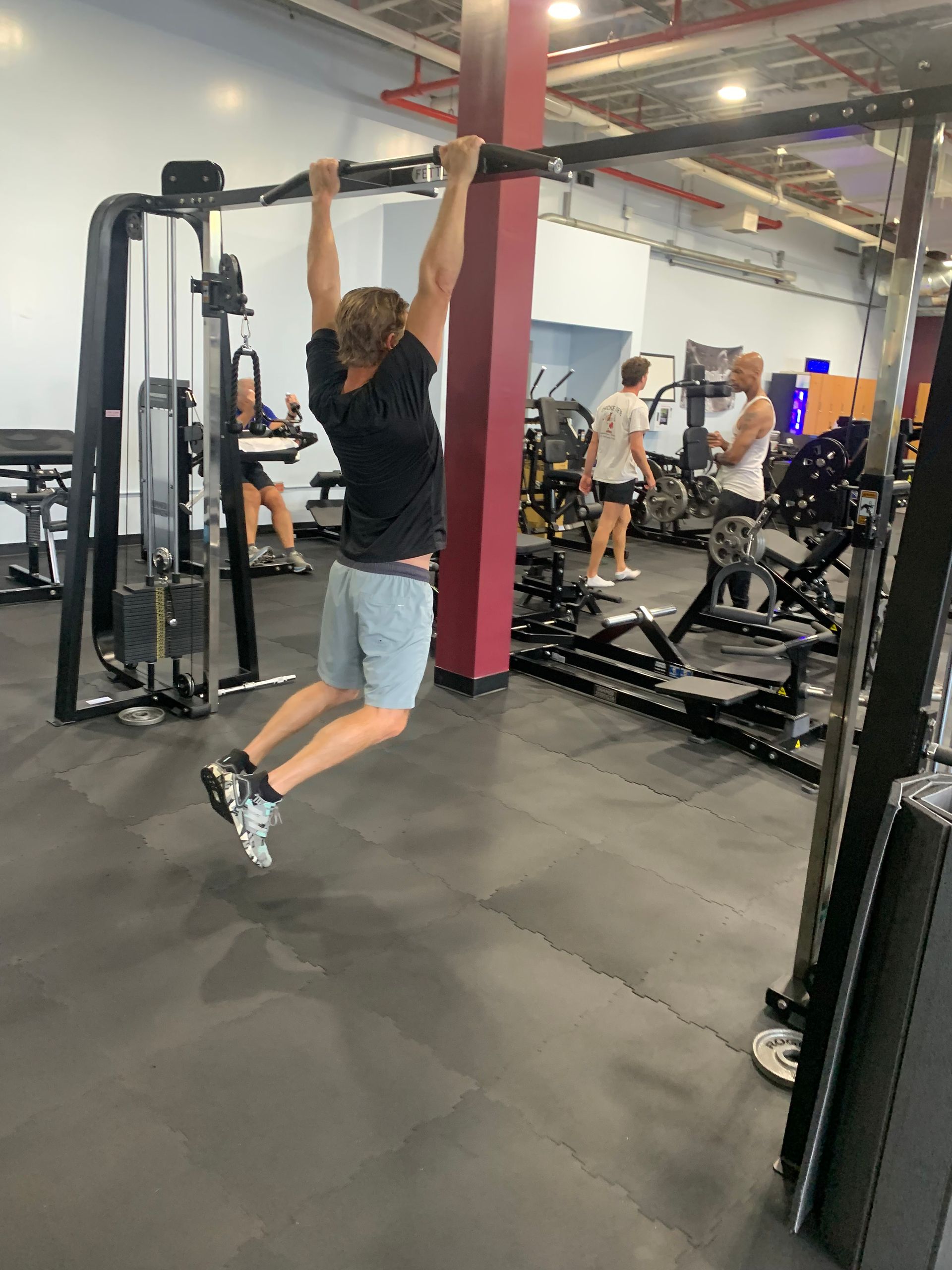 A man is doing a pull up in a gym.
