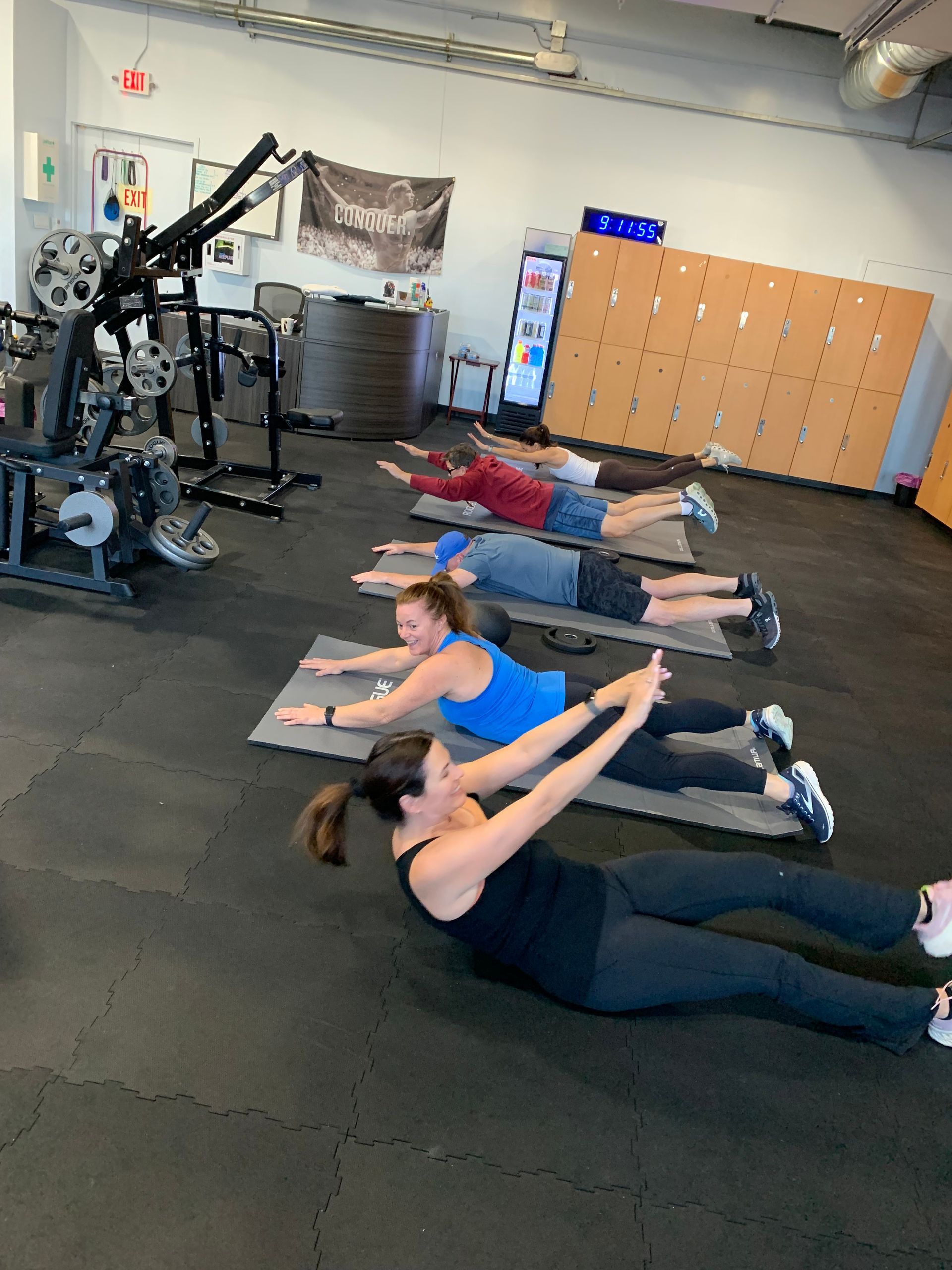A group of people are doing exercises on mats in a gym.