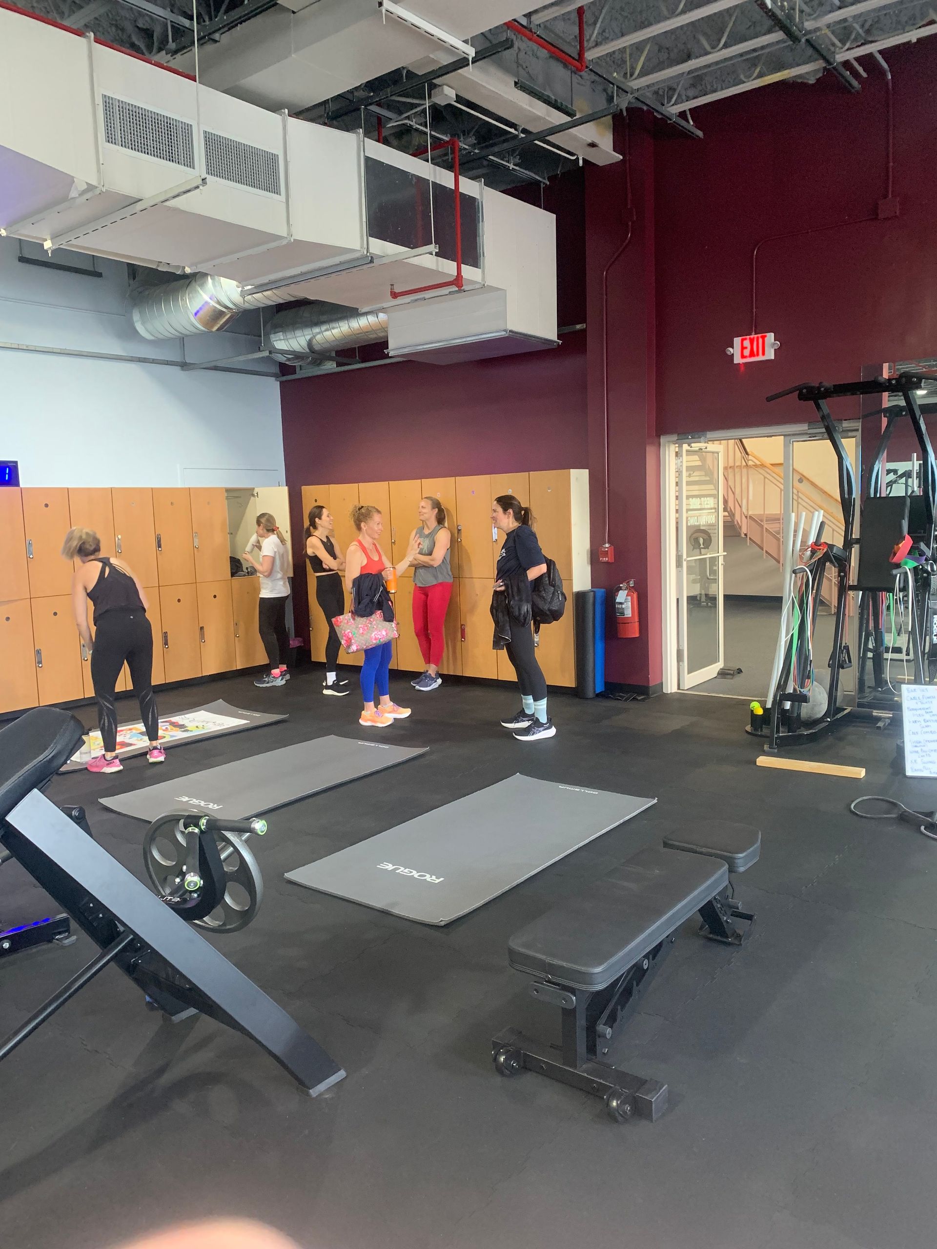 A group of people are standing in a gym talking to each other.