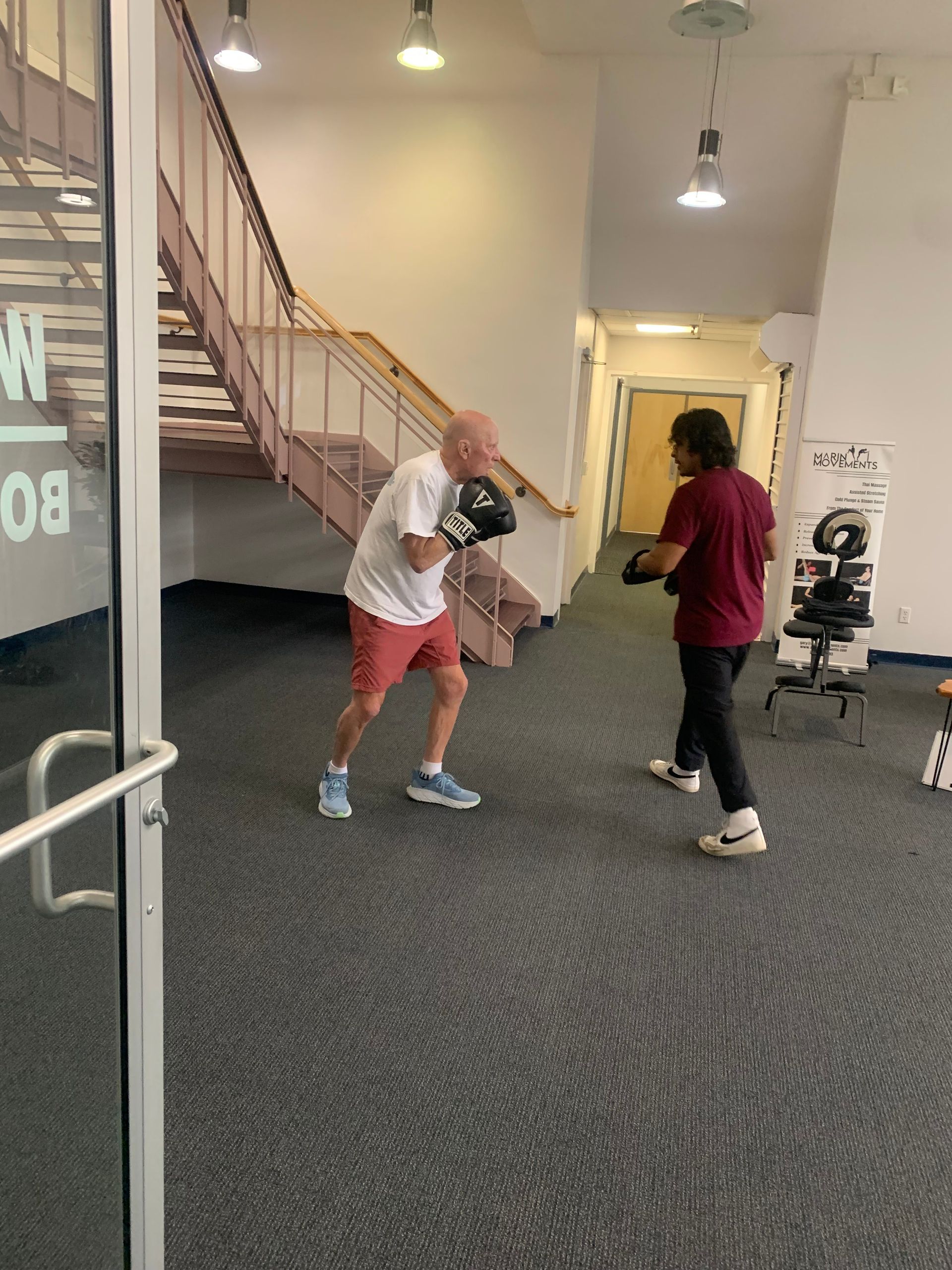 A man wearing boxing gloves is practicing with another man