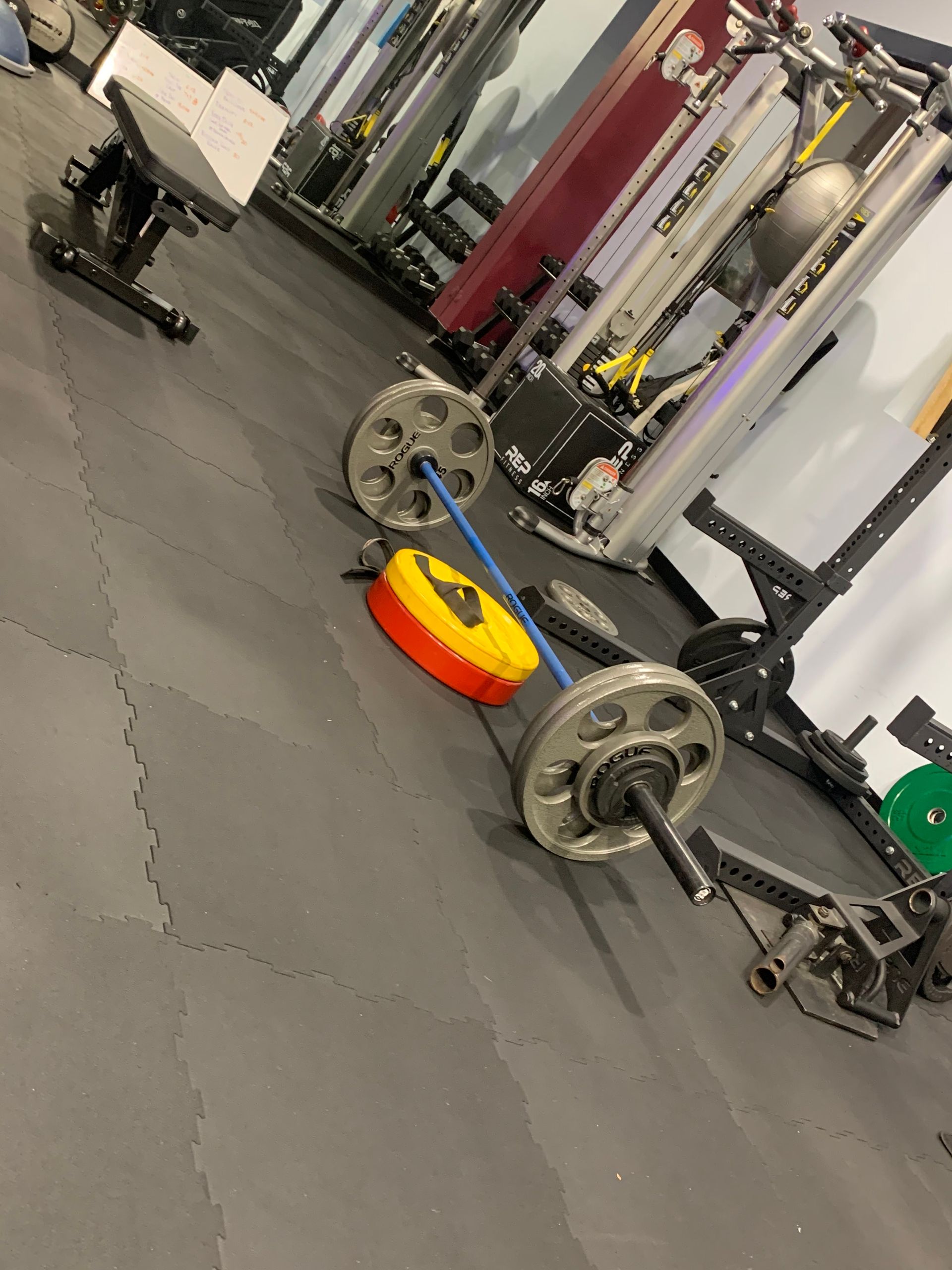 A barbell is laying on the floor in a gym.