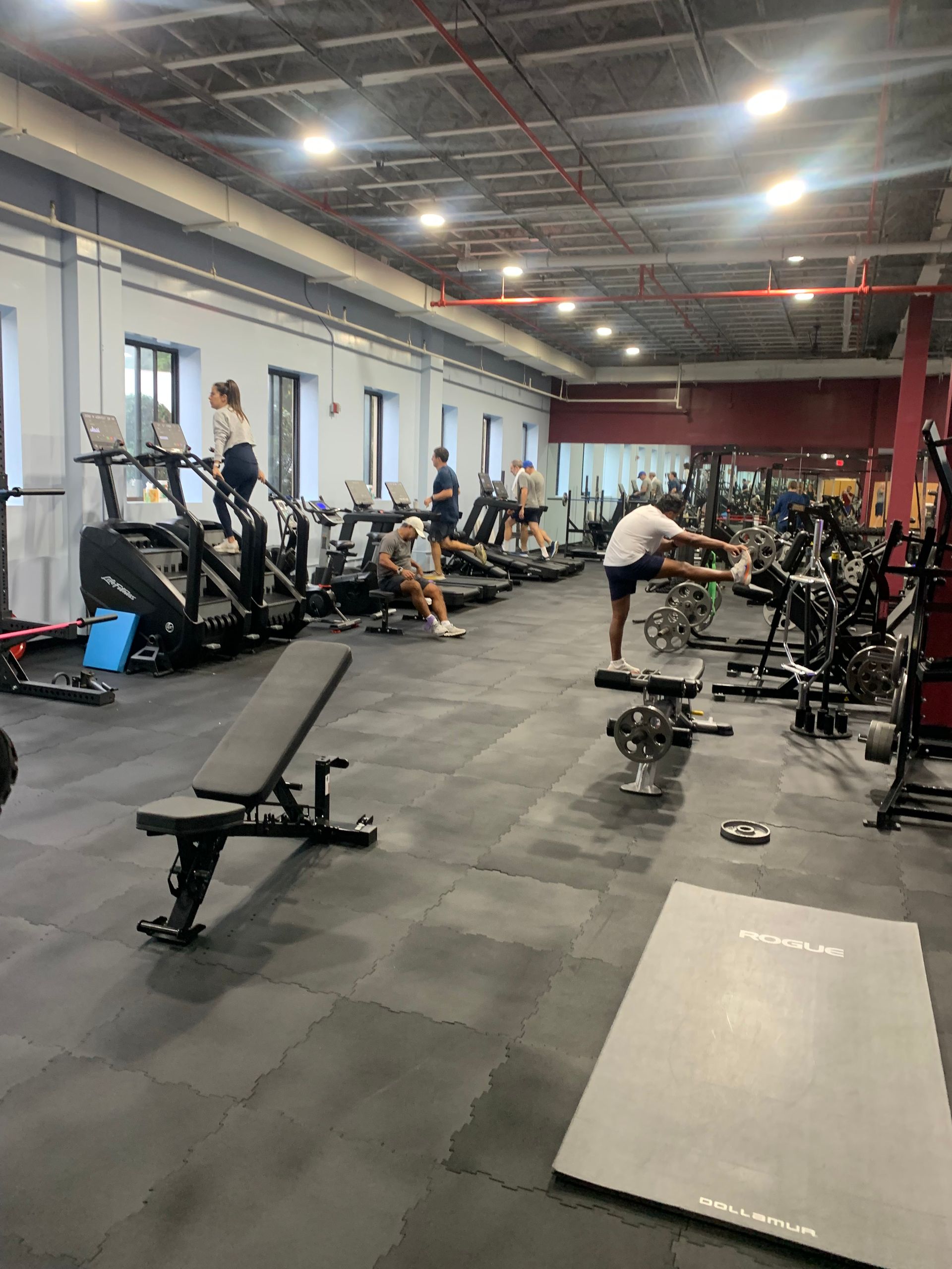 A gym filled with lots of exercise equipment and people.