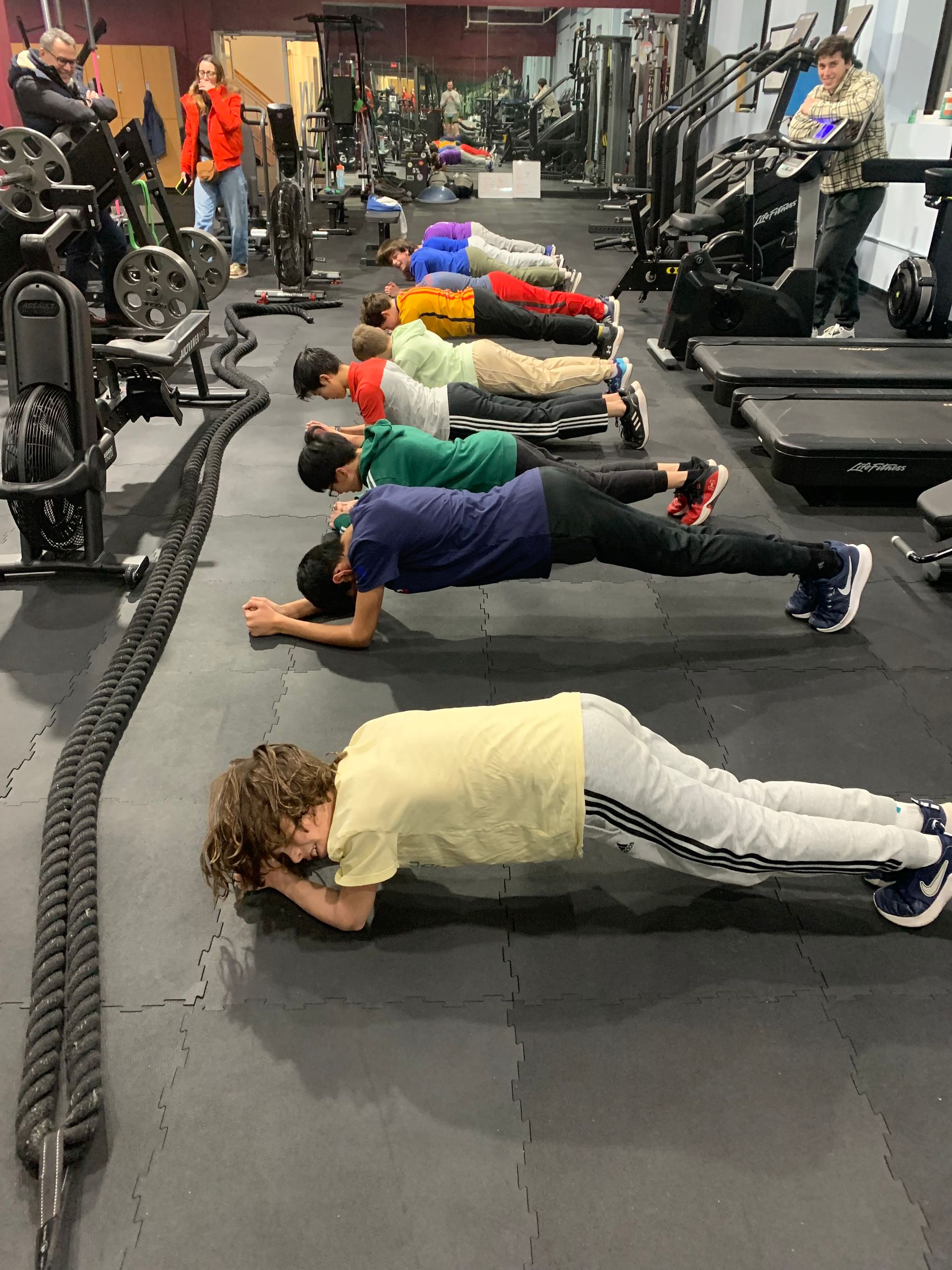 A group of children are doing push ups in a gym.
