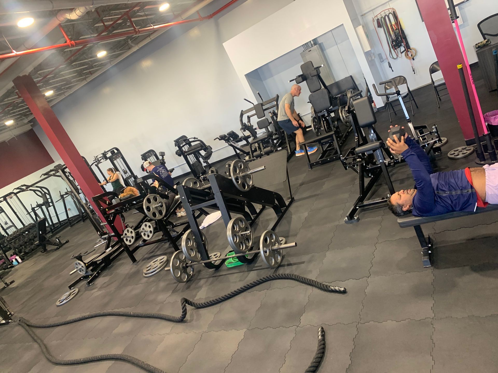 A woman is laying on a bench in a gym.