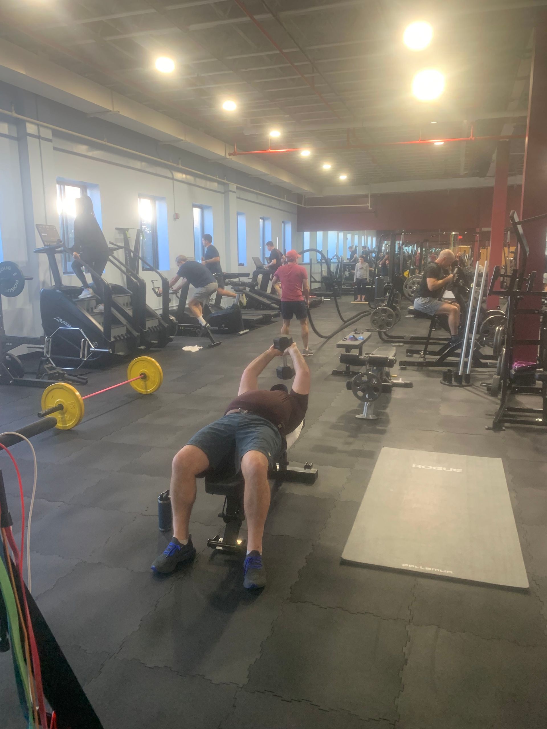 A man is sitting on a bench in a gym lifting a barbell.