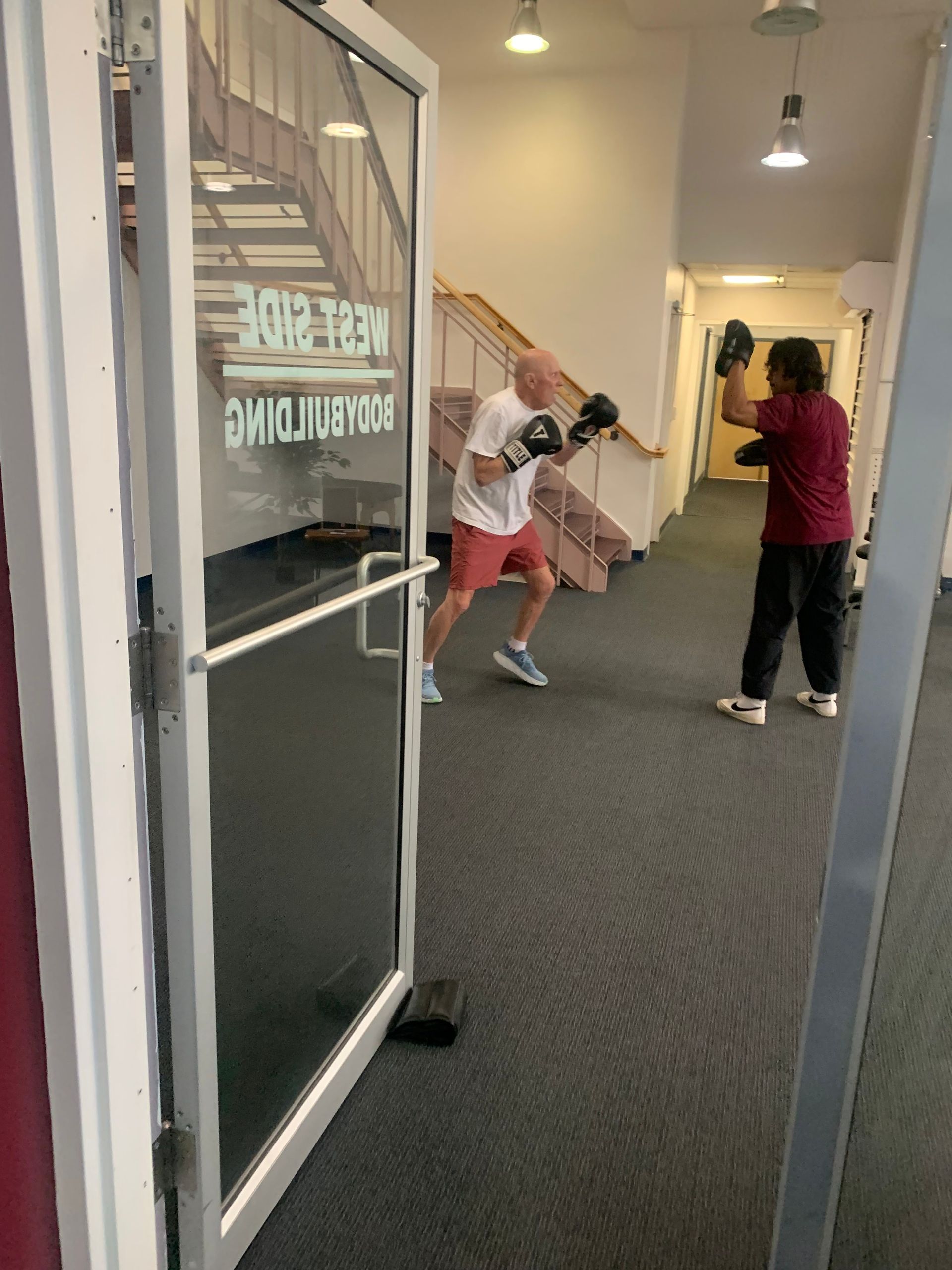 A man wearing boxing gloves is practicing in a gym.