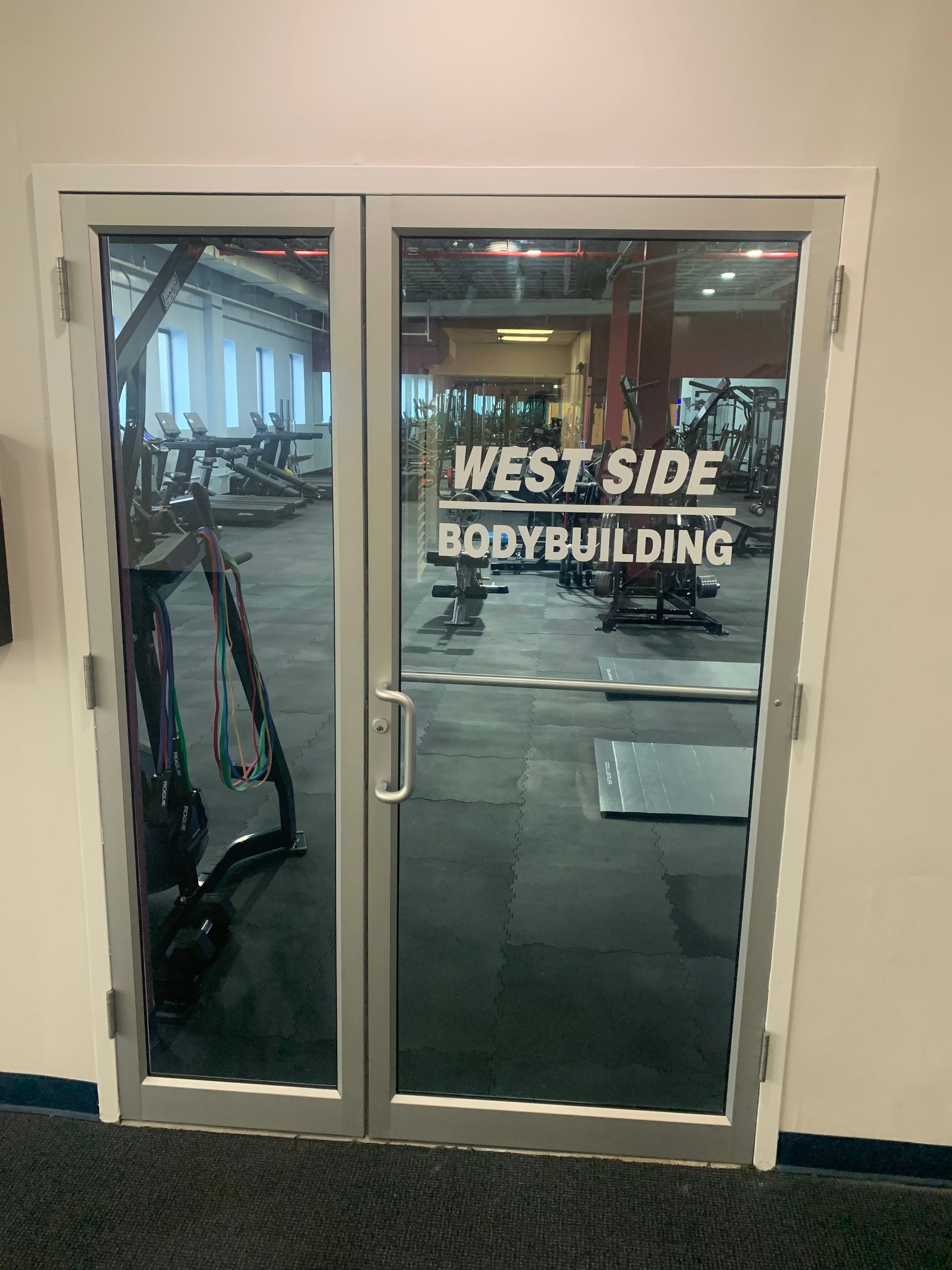 A gym with a glass door and a sign that says west side bodybuilding.