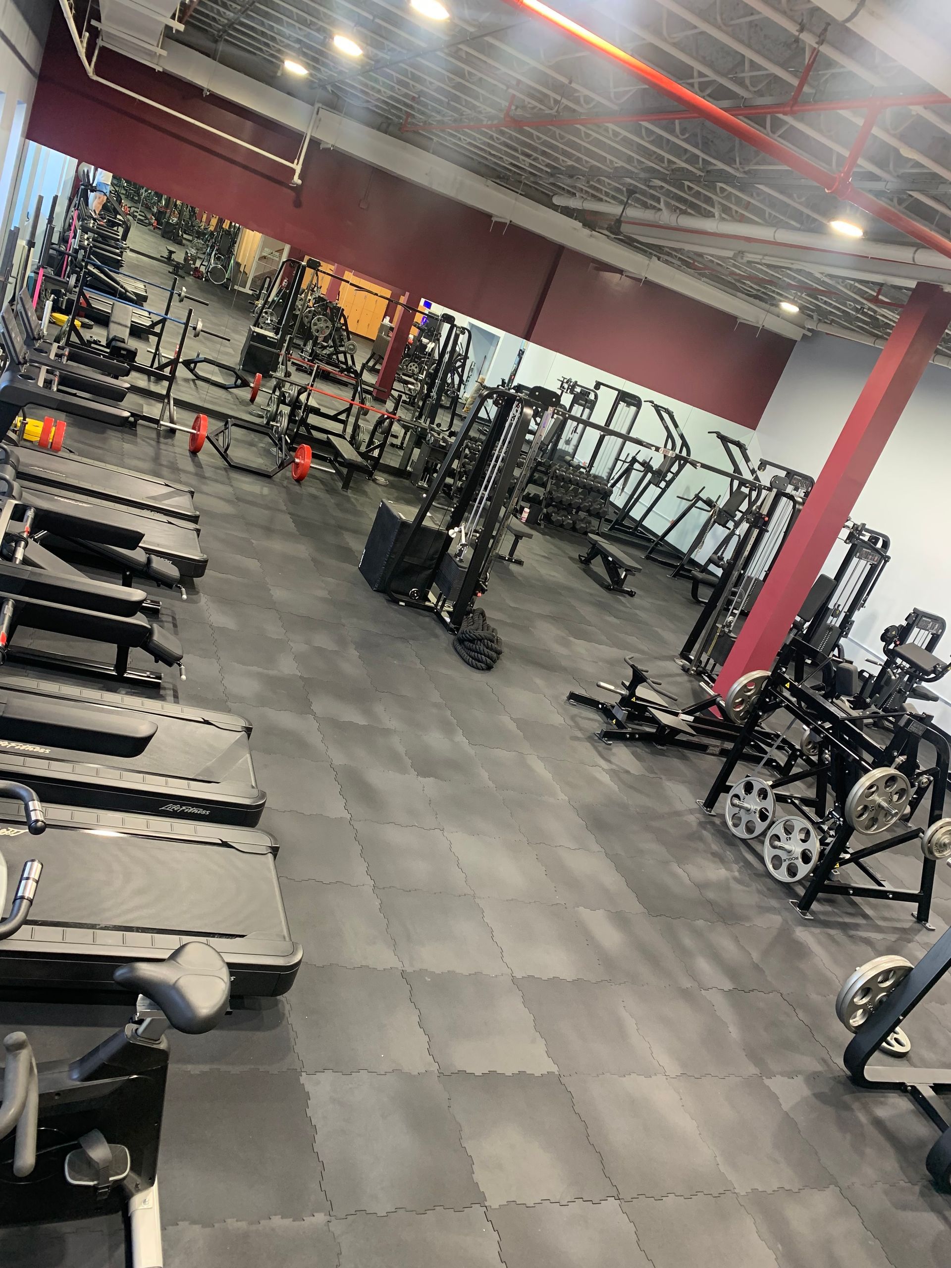 A gym filled with lots of exercise equipment and a large mirror.