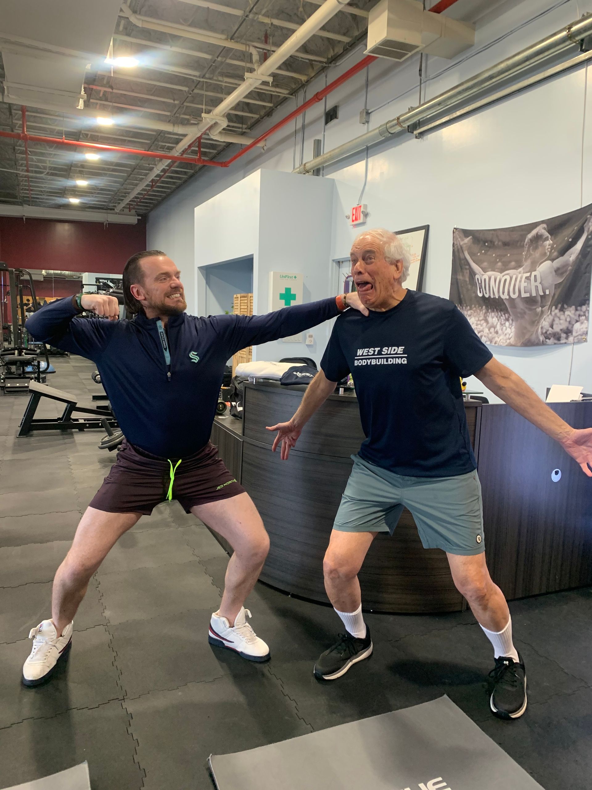 Two men are standing next to each other in a gym.