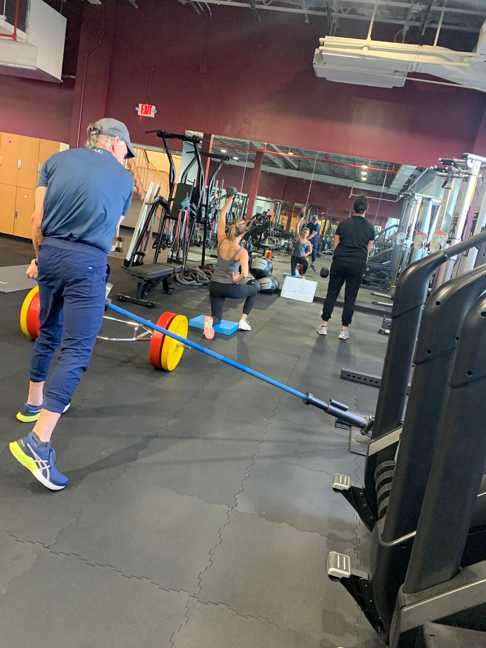 A man is pulling a barbell with a rope in a gym.