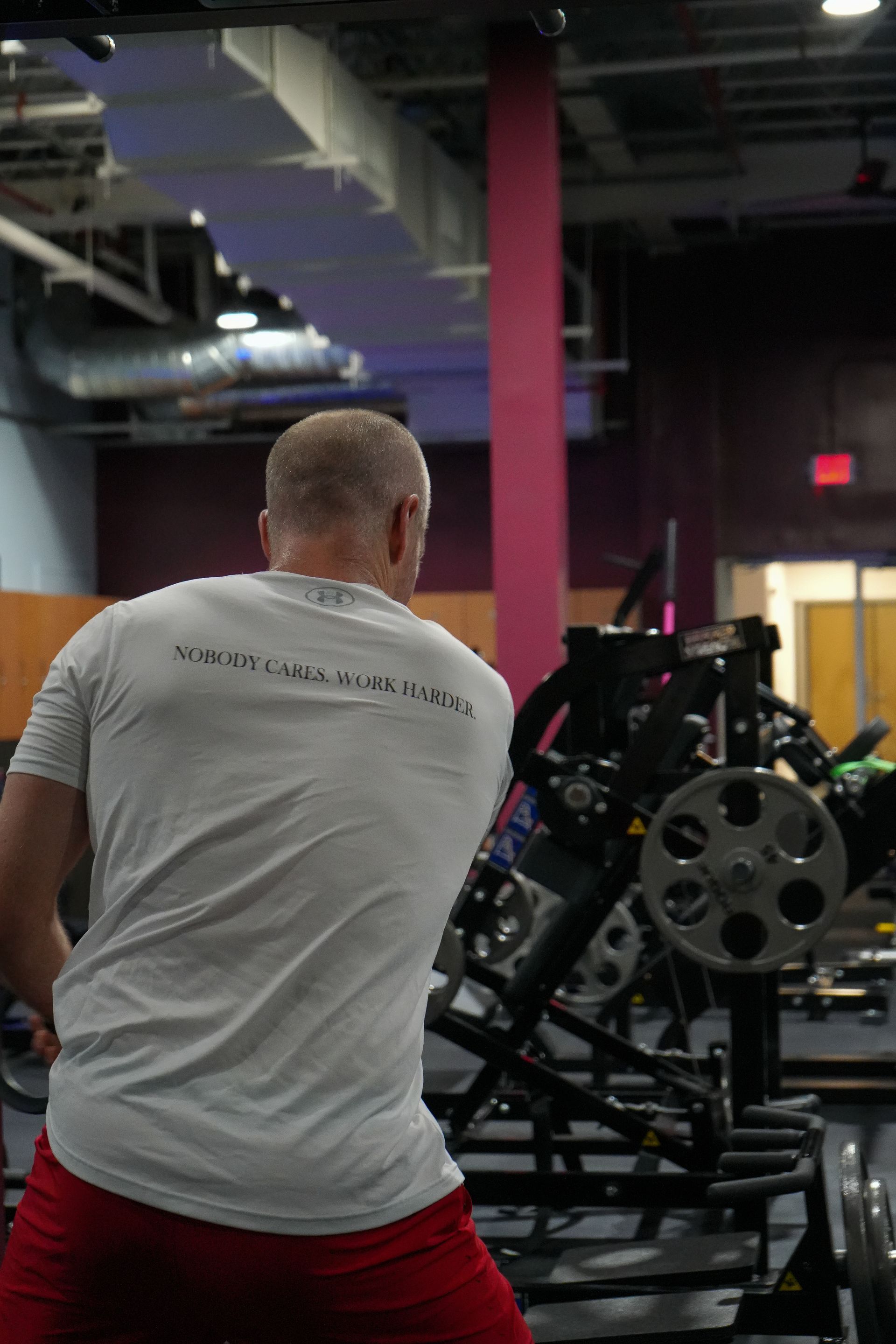 A man in a white shirt is standing in a gym.