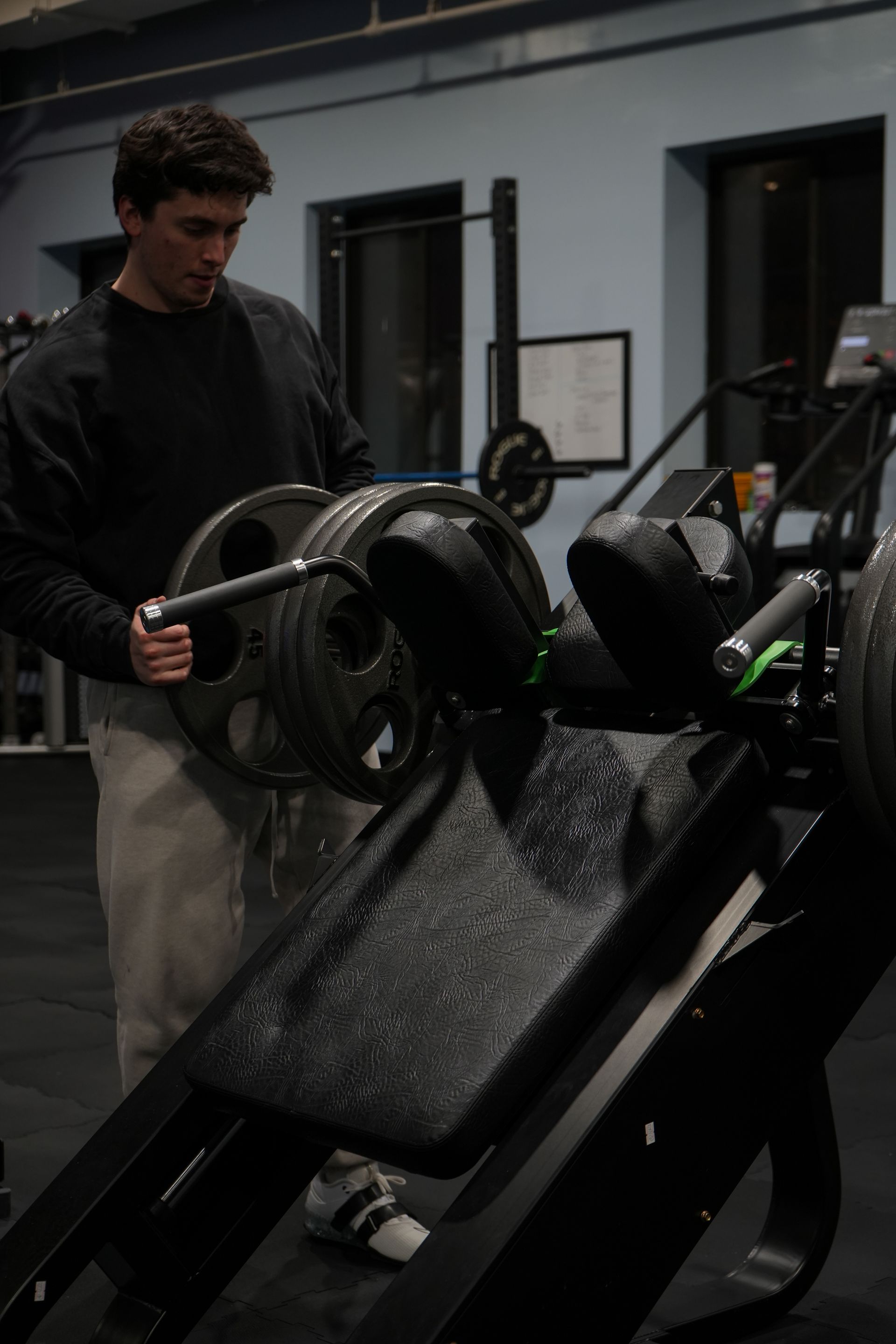 A man is lifting a barbell on a machine in a gym.