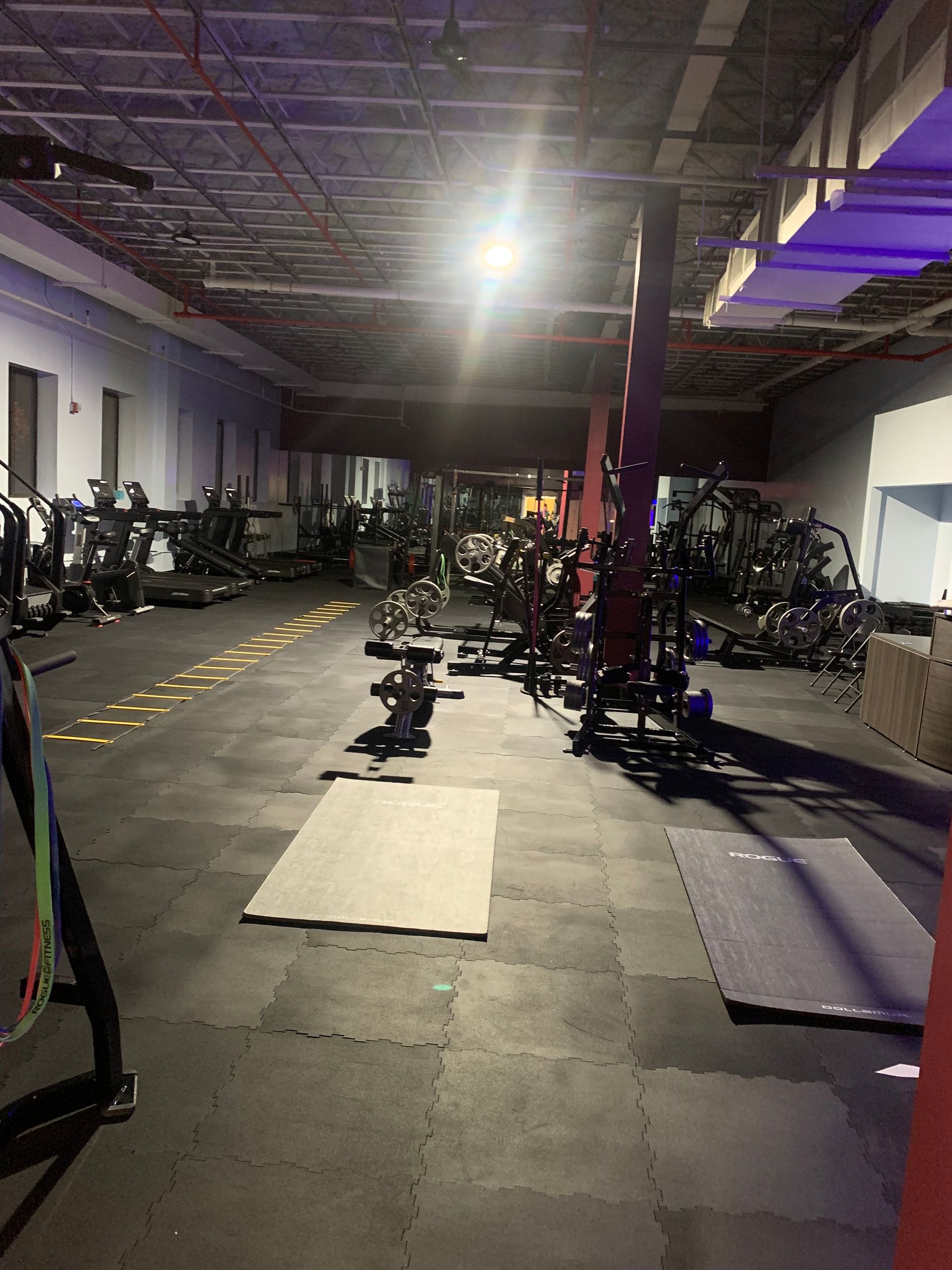 A gym filled with lots of exercise equipment and a purple light.