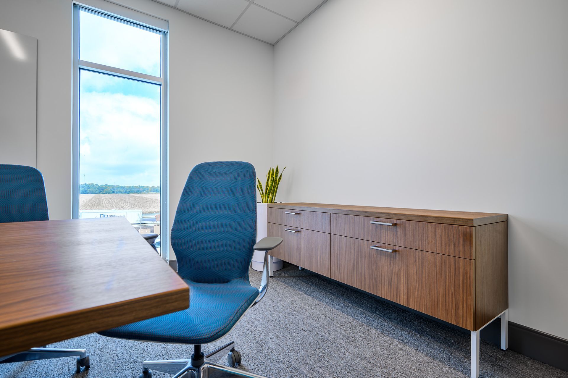 An office with a blue chair and wooden cabinets