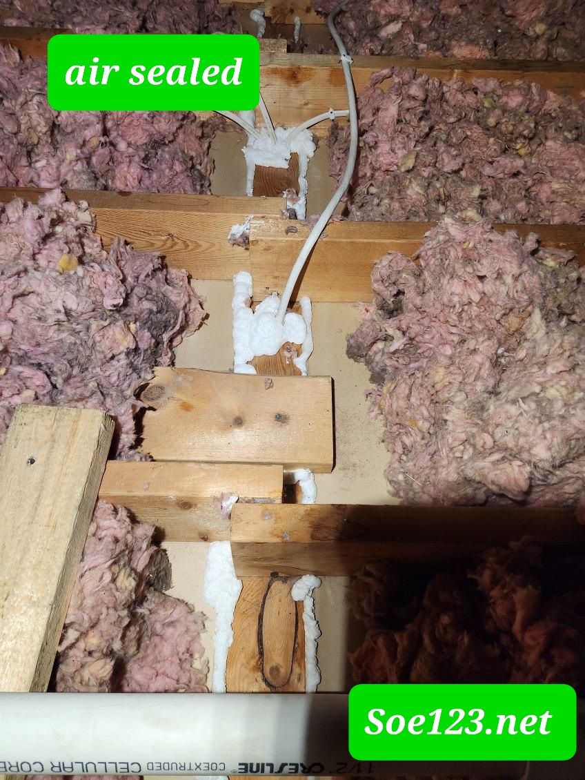 A picture of an attic with a green sign that says air sealed