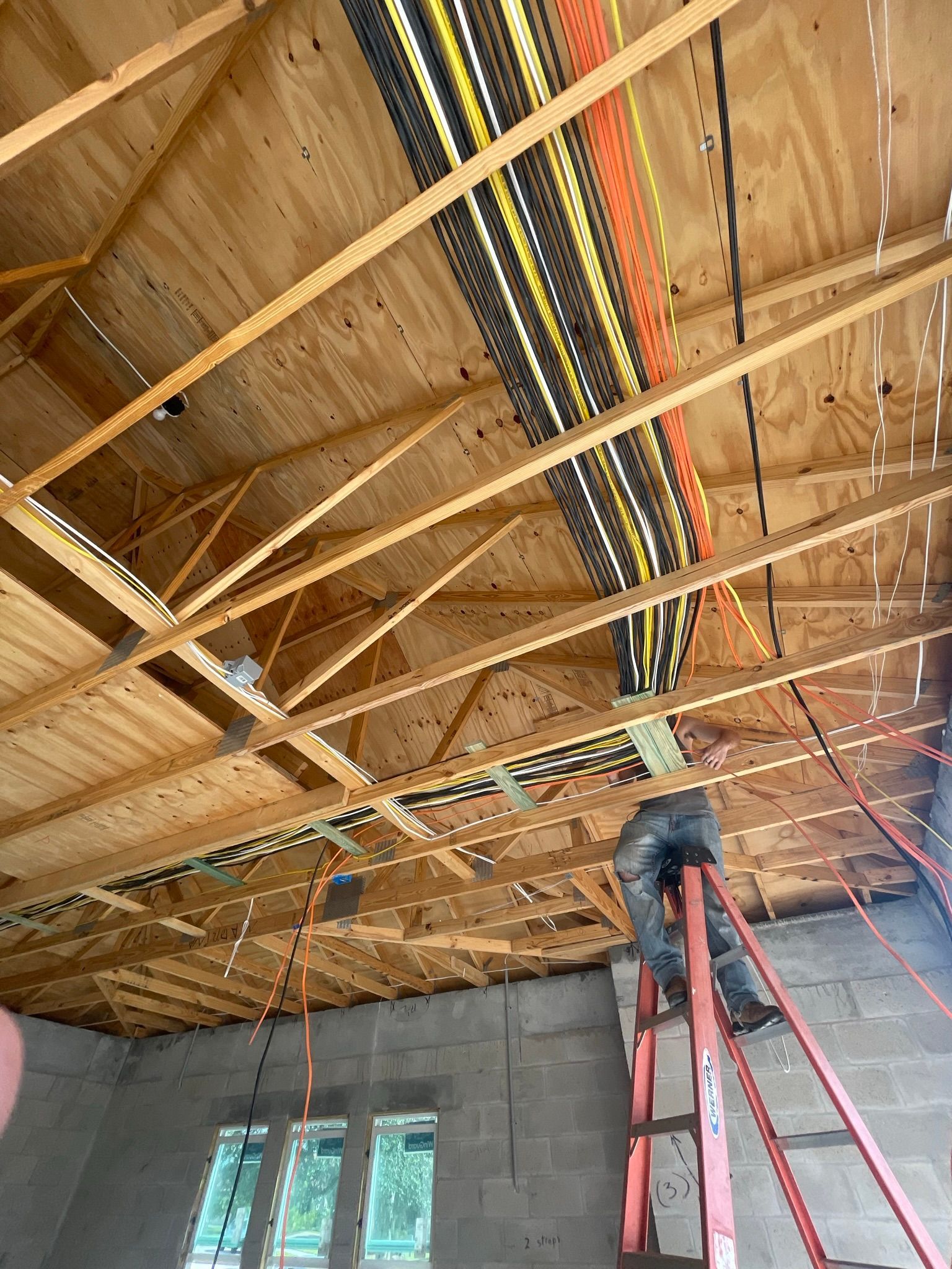 A man is standing on a ladder working on the ceiling of a building.