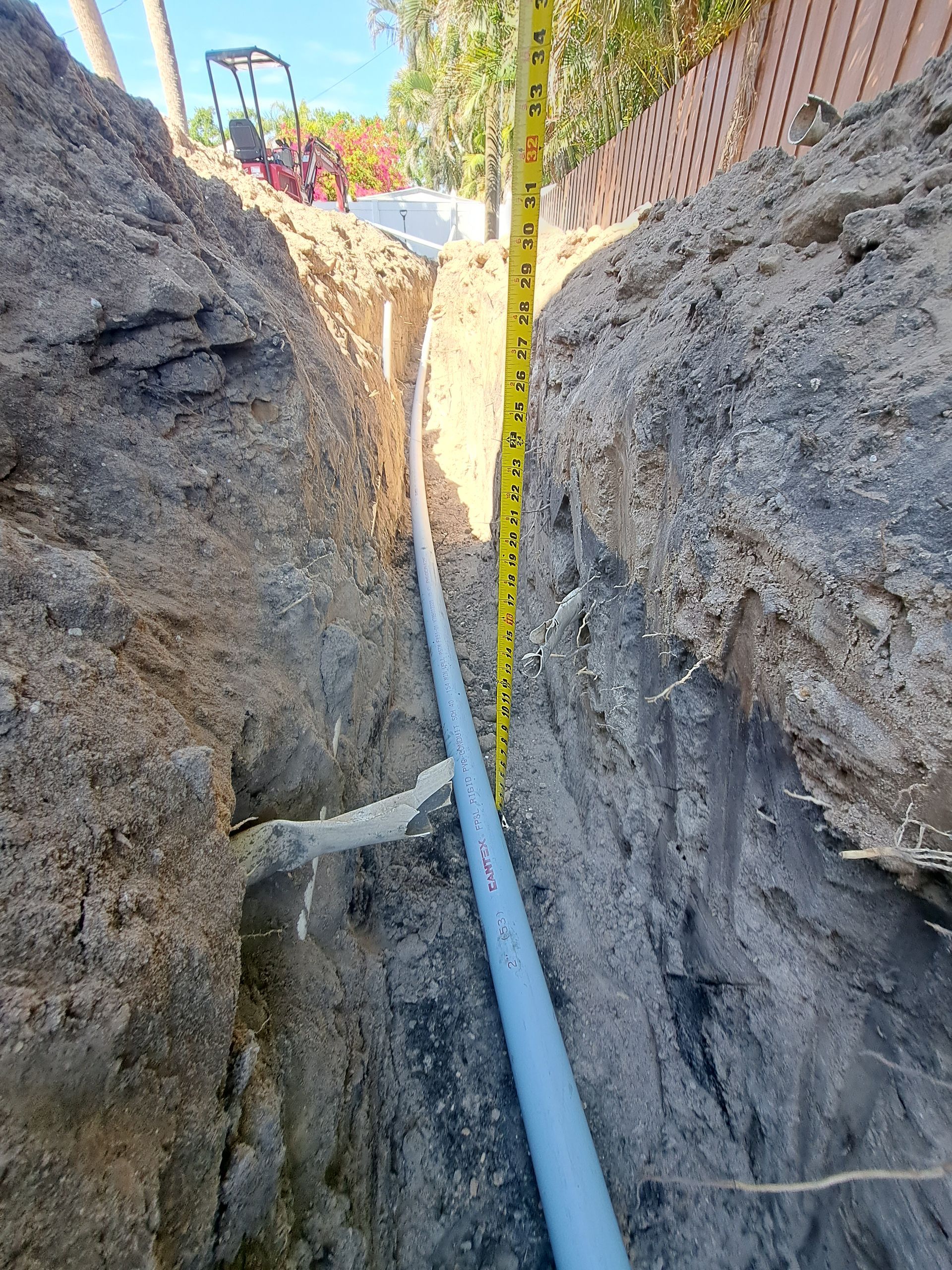 A pipe is being measured in a trench with a tape measure.