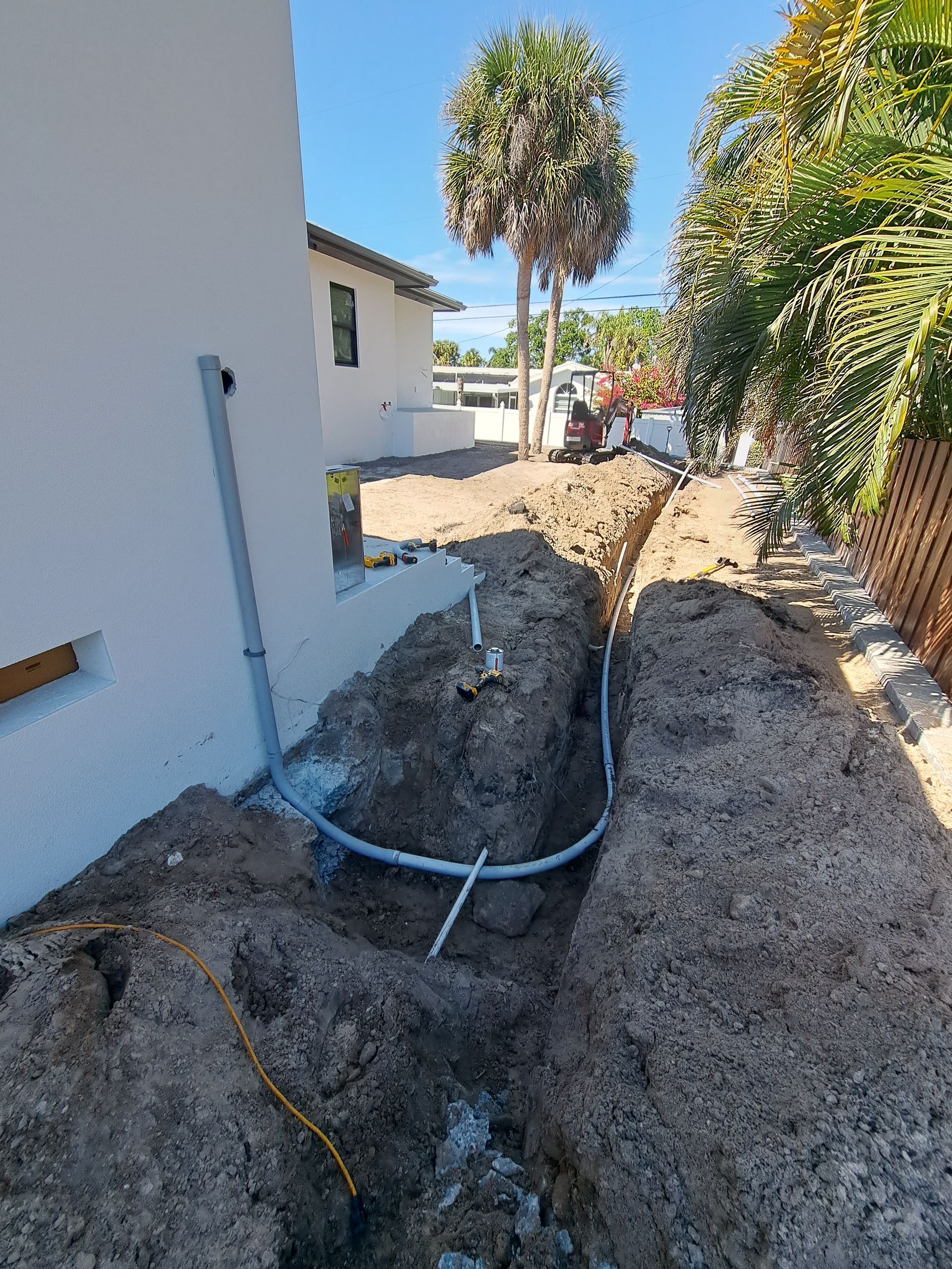 A pipe is being installed in the dirt next to a house.