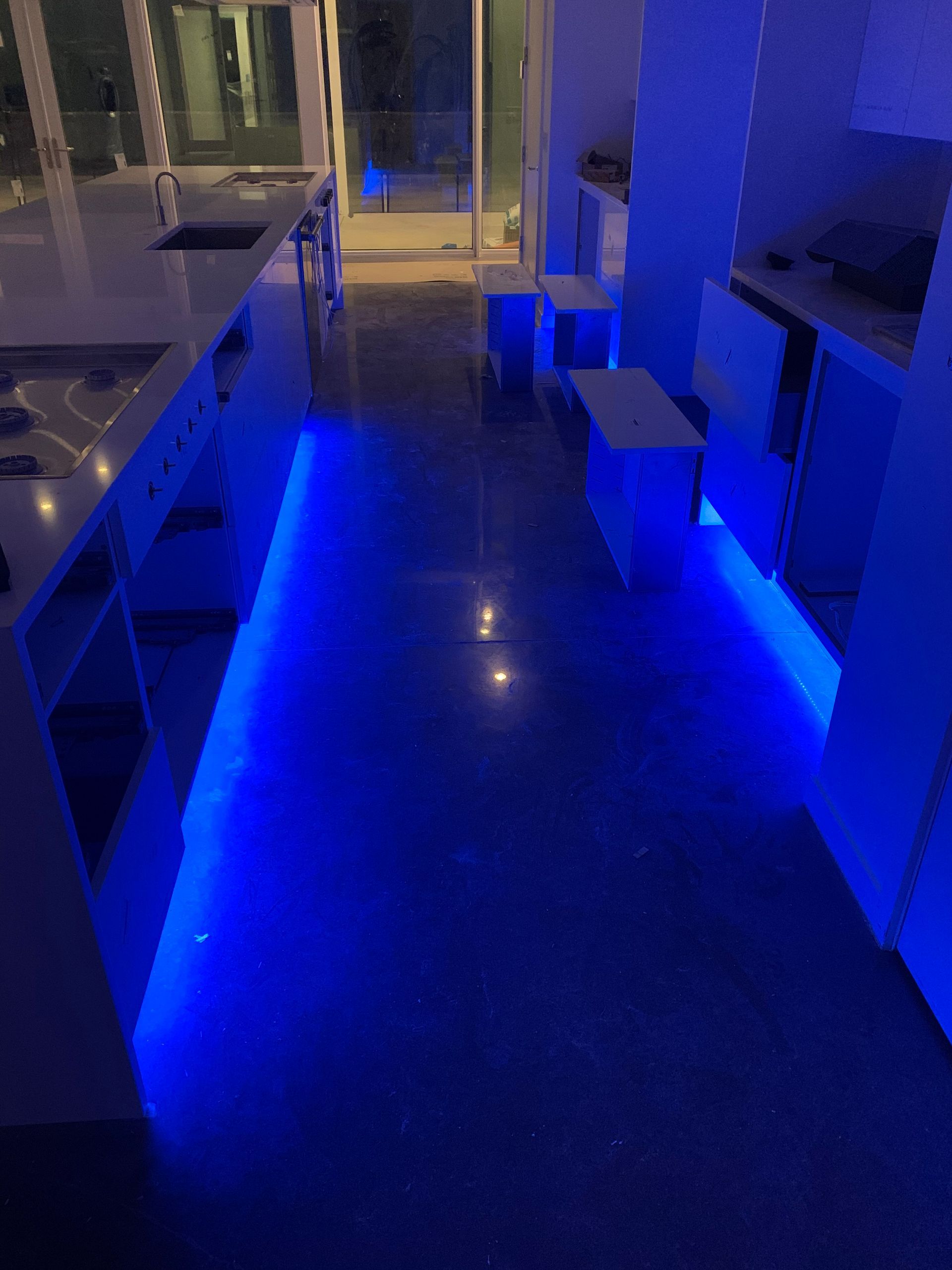 A kitchen with blue lights on the floor and walls.